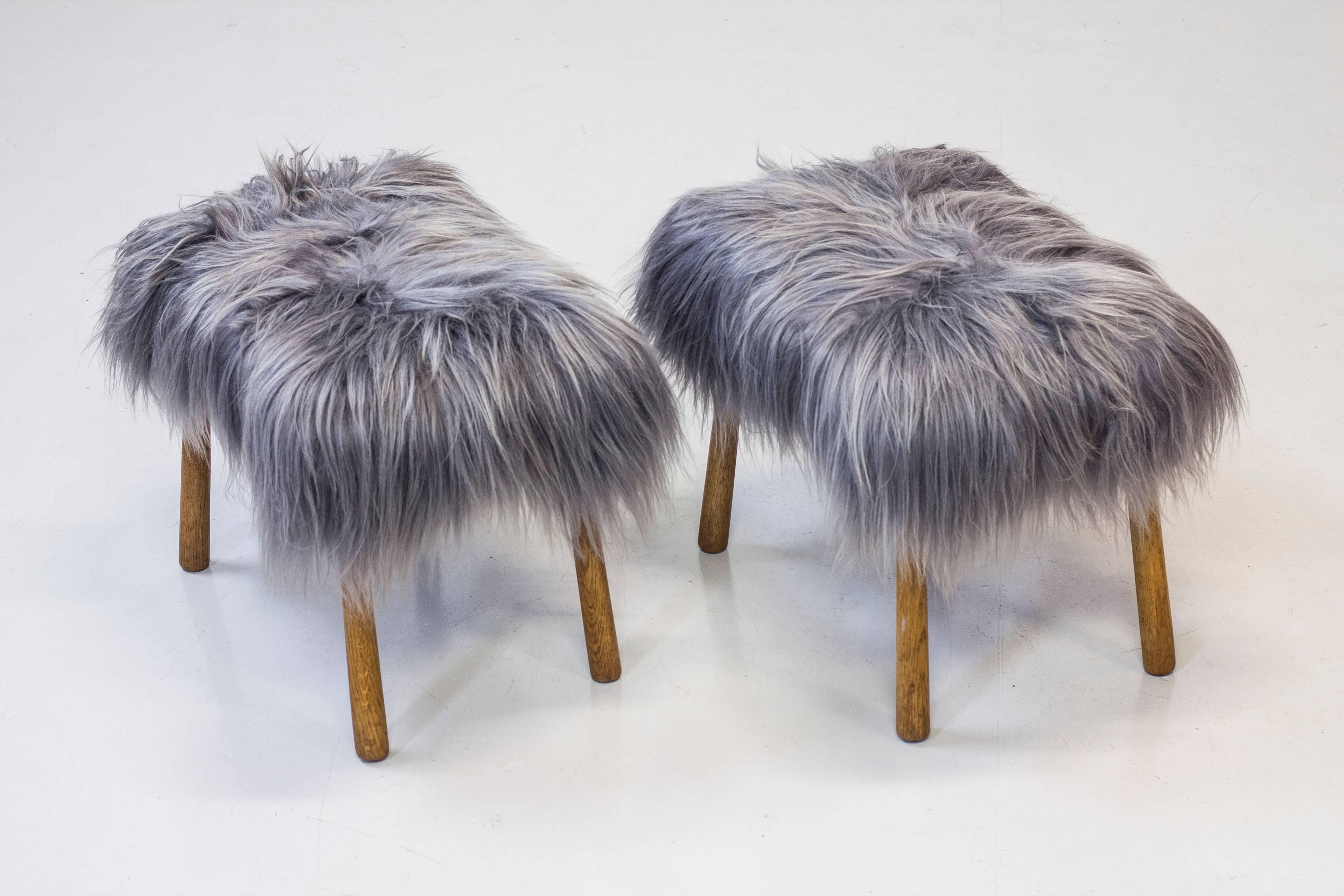 Pair of stools designed by unknown Danish interior architect. Produced by cabinet maker in Denmark around the 1940s. Standing on four club shaped solid oak legs with oil finish. Reupholstered with grey Icelandic sheepskin. Excellent condition with