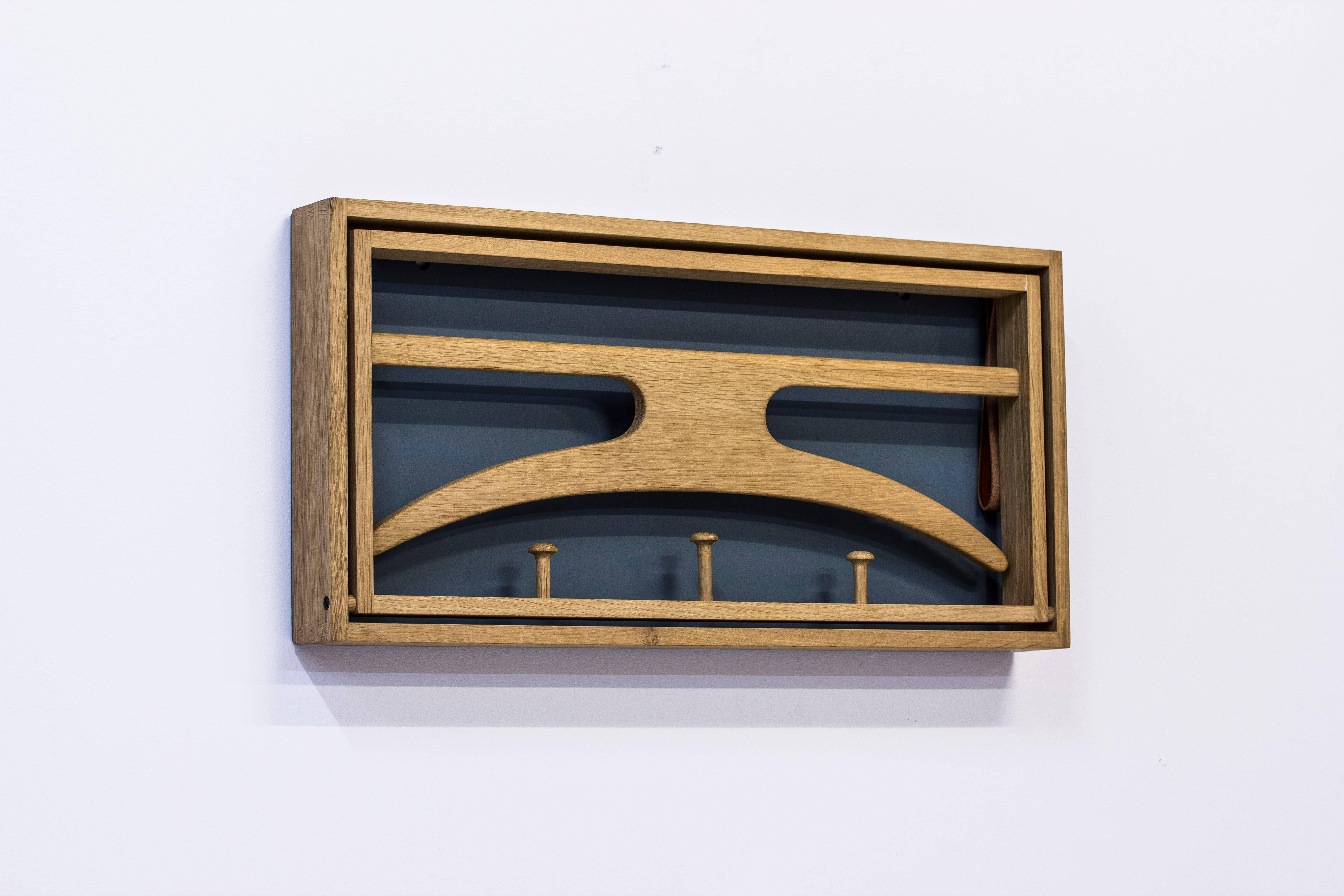 Wall mounted valet designed by Adam Hoff & Poul Østergaard. Produced in Denmark during the late 1950s by Virum Møbelsnedkeri. Solid oak frame with visible joinery, original leather straps and lacquered back part. Very good condition with light wear
