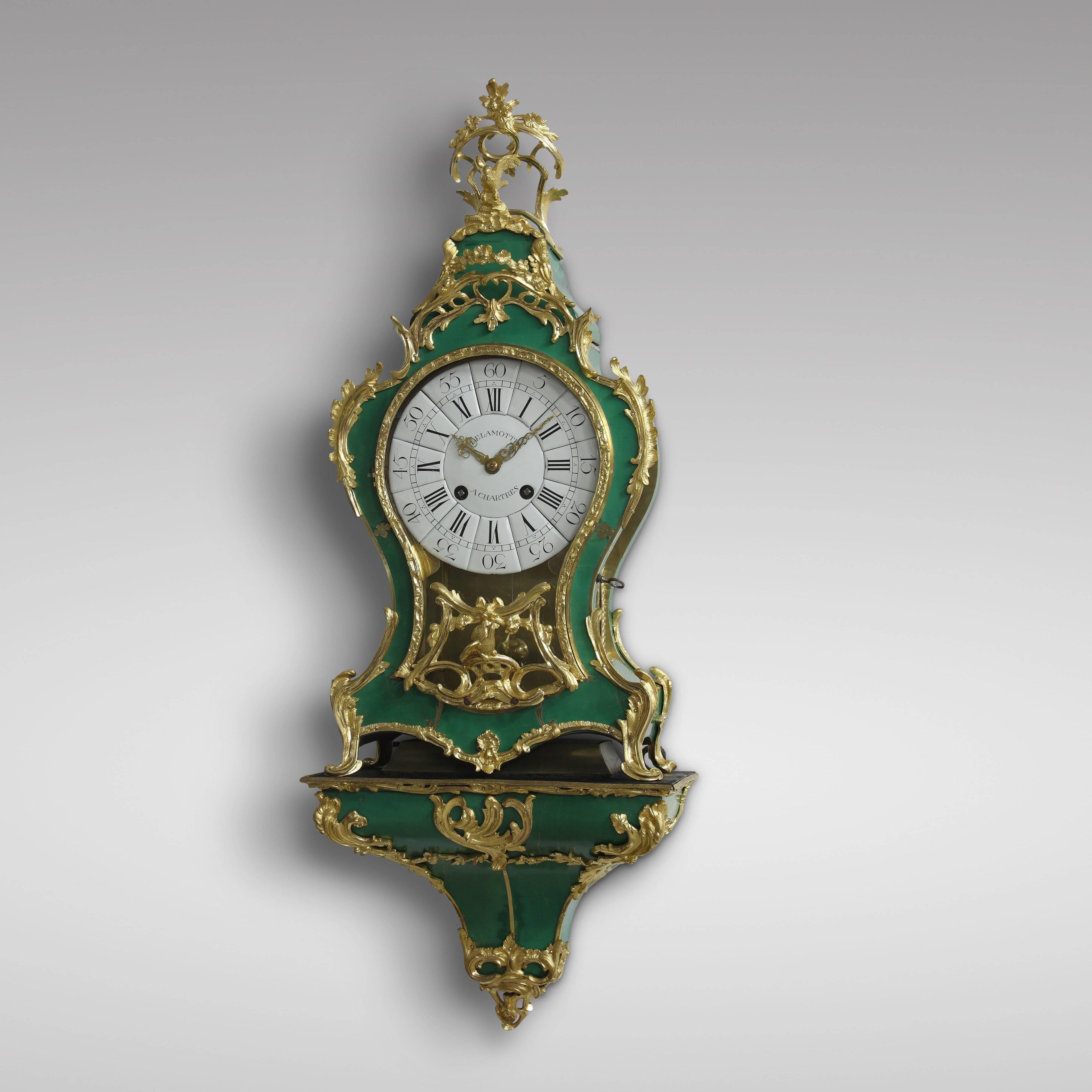 The case with green-backed Horn veneer “Corne Verte” and ormolu bronze applied, signed DELAMOTTE A CHARTRES on the dial and De La Motte A Chartres on the backplate of the movement.
The case and the console with C-scrolls, flowers, leaves and