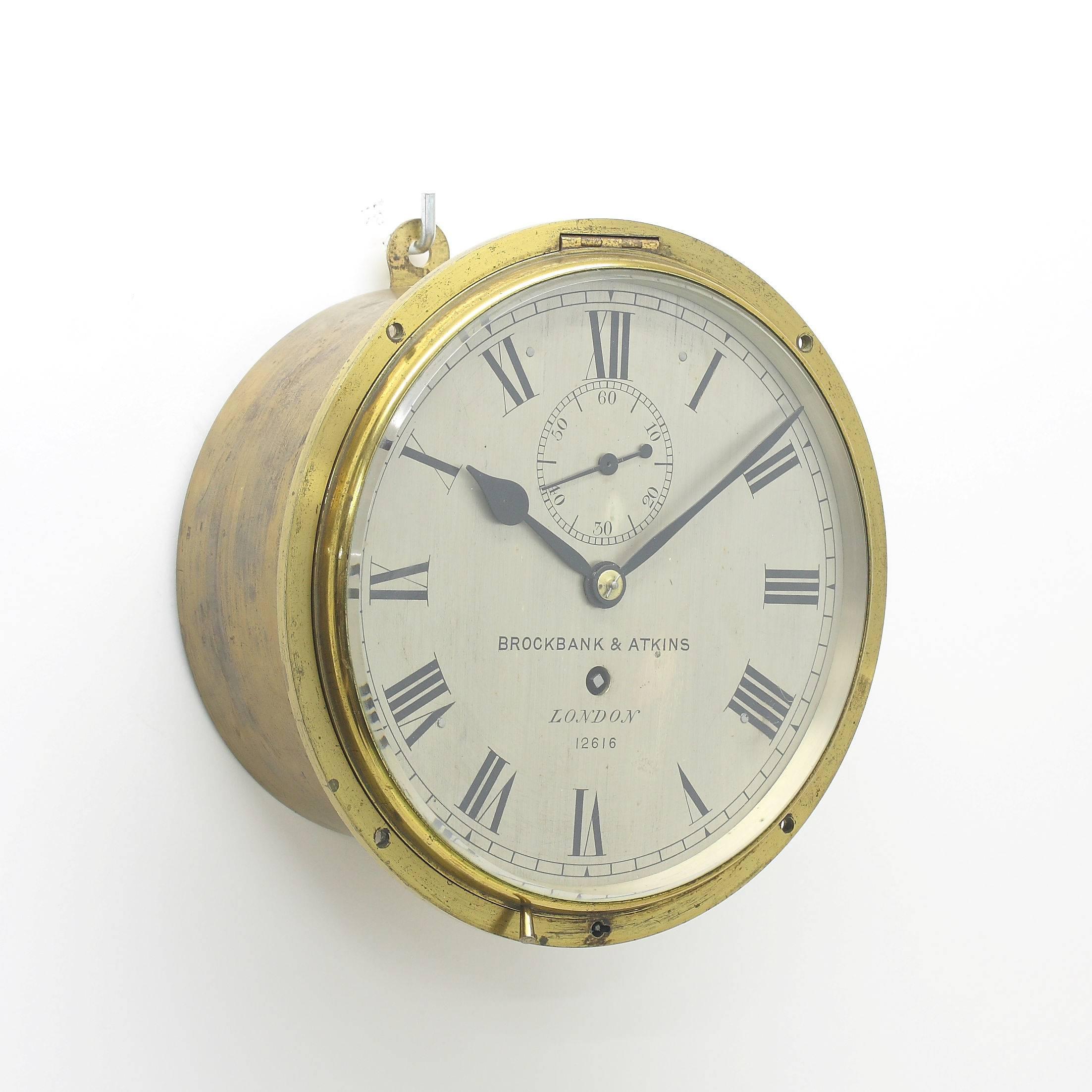 English bulkhead clock of good precision, with the main part of the case made to be recessed, now with removable keyhole hanger allowing it to be hung as is. Solid brass case with hinge above and lock and key below, The silvered brass dial with