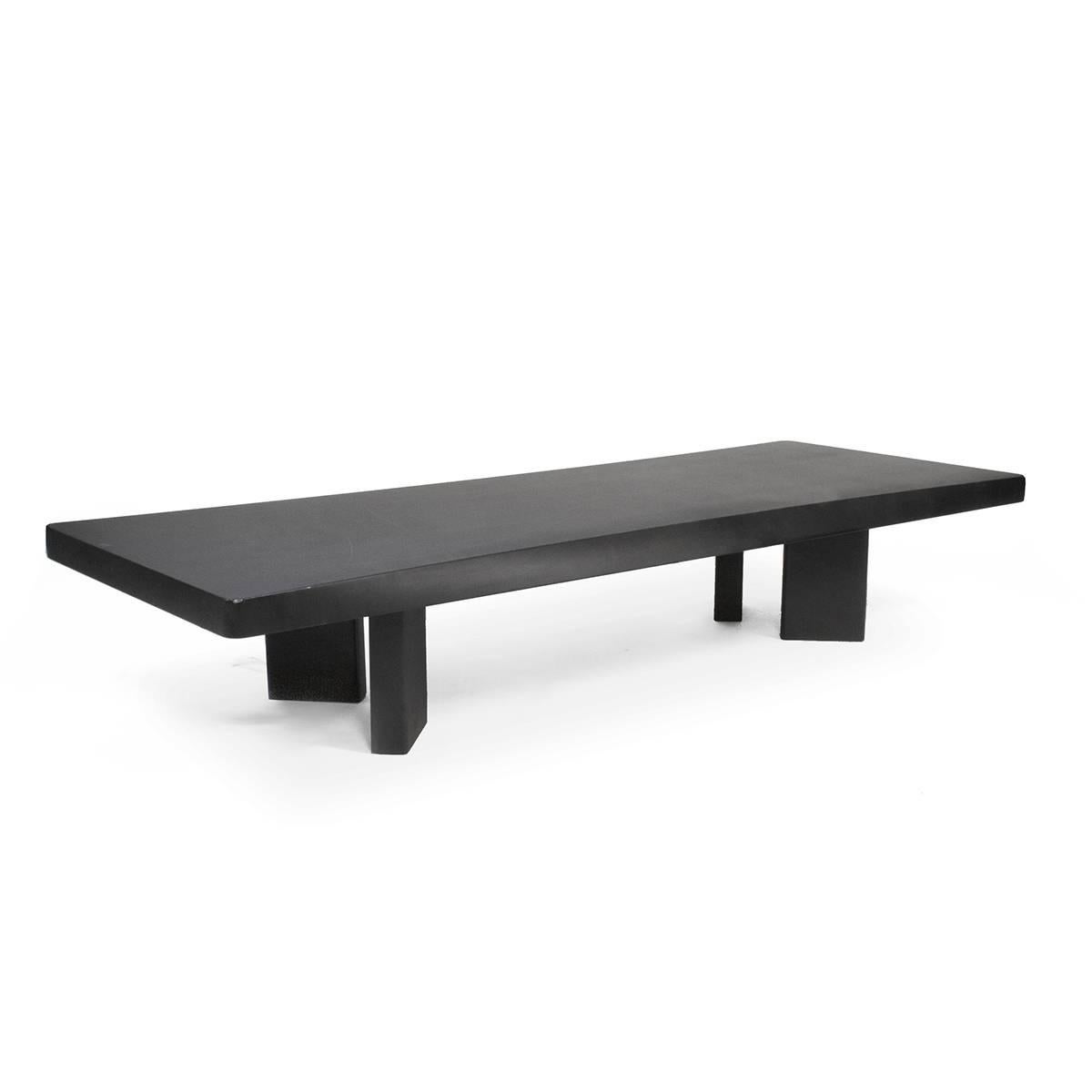 Low table in matte black painted wood. The thickness of the top and its concave edge strongly characterise the model in formal terms and create a surprising sensation of lightness. 515 02