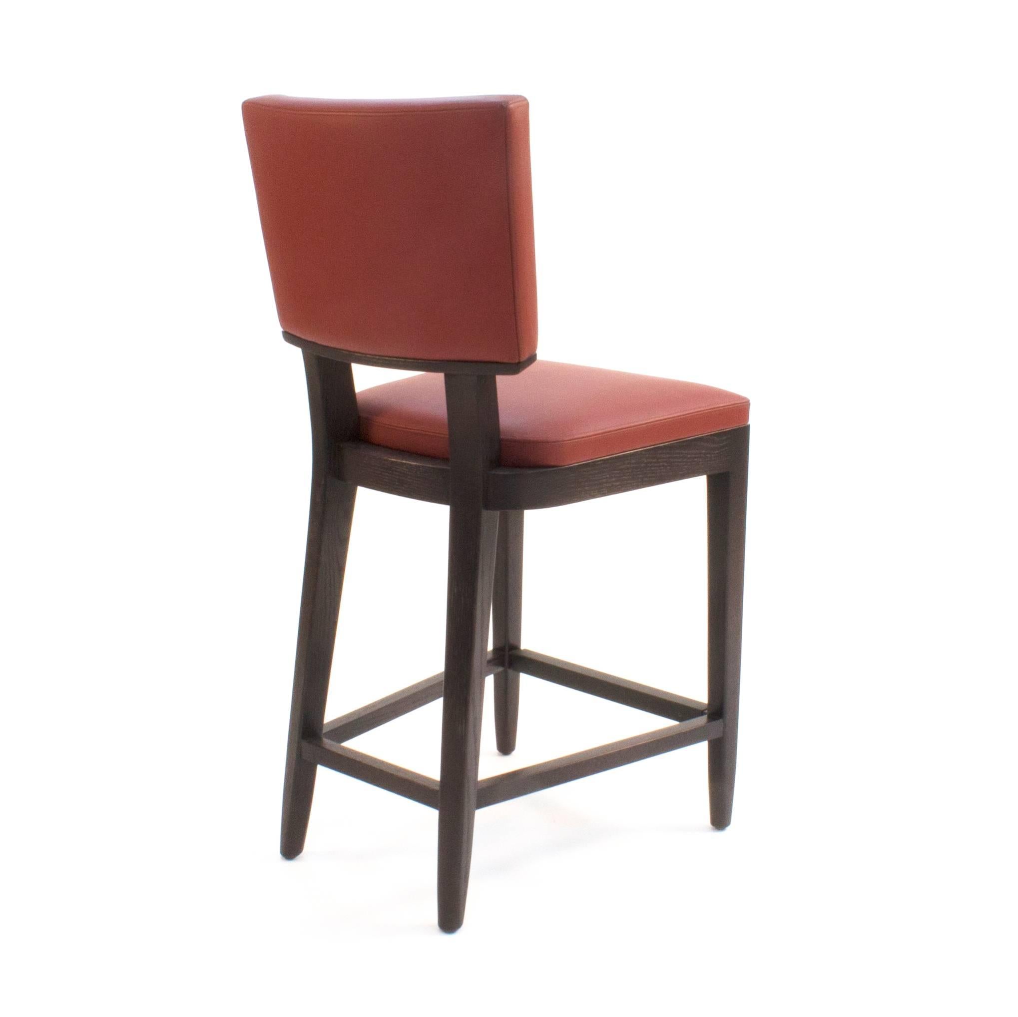 Upholstered stool with floating, curved back and exposed wood frame upholstered in CL Leather.