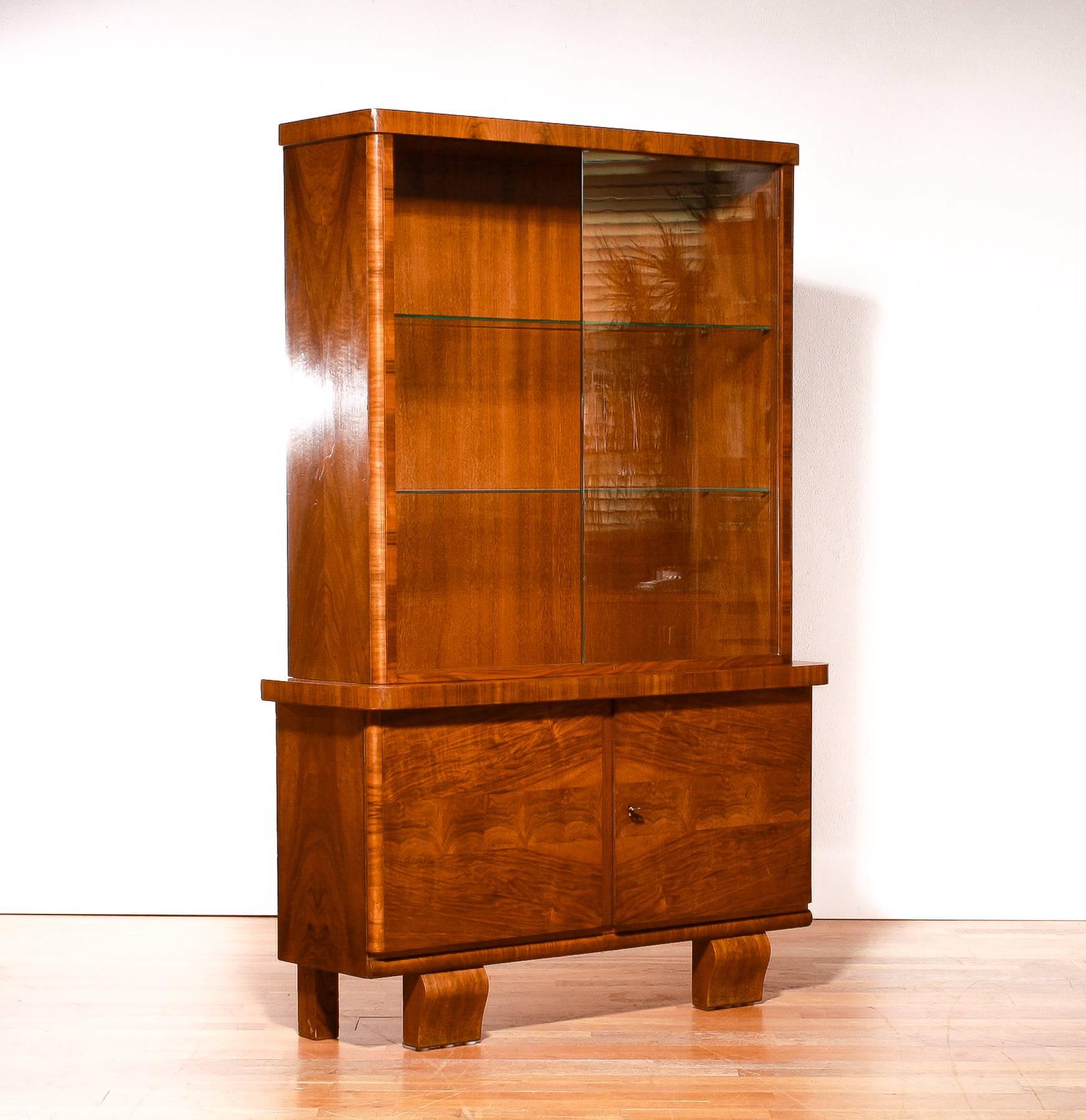Beautiful Art Deco display cabinet.

The cabinet is made of beautiful walnut veneer and is in a perfect condition.

The original sliding glass doors are still entirely intact. (Just one little invisible chip on the inside of the