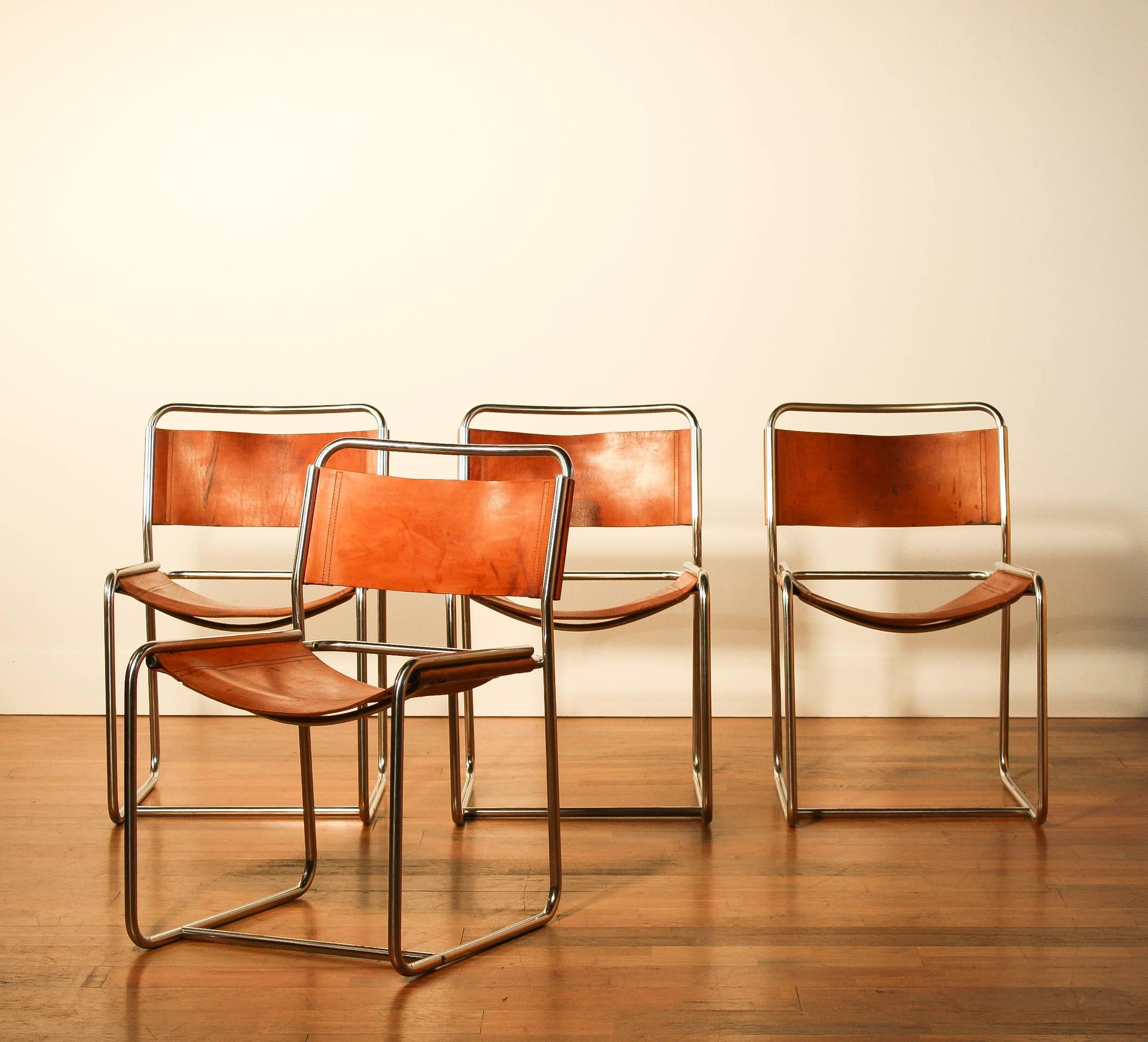 A nice set of four dining chairs designed by Paul Ibens & Clair Bataille.
The seat and the backrest are made of sturdy cognac leather. 
The frame consists of steel tube that is shaped like a cube. 
The chairs are in a very nice used