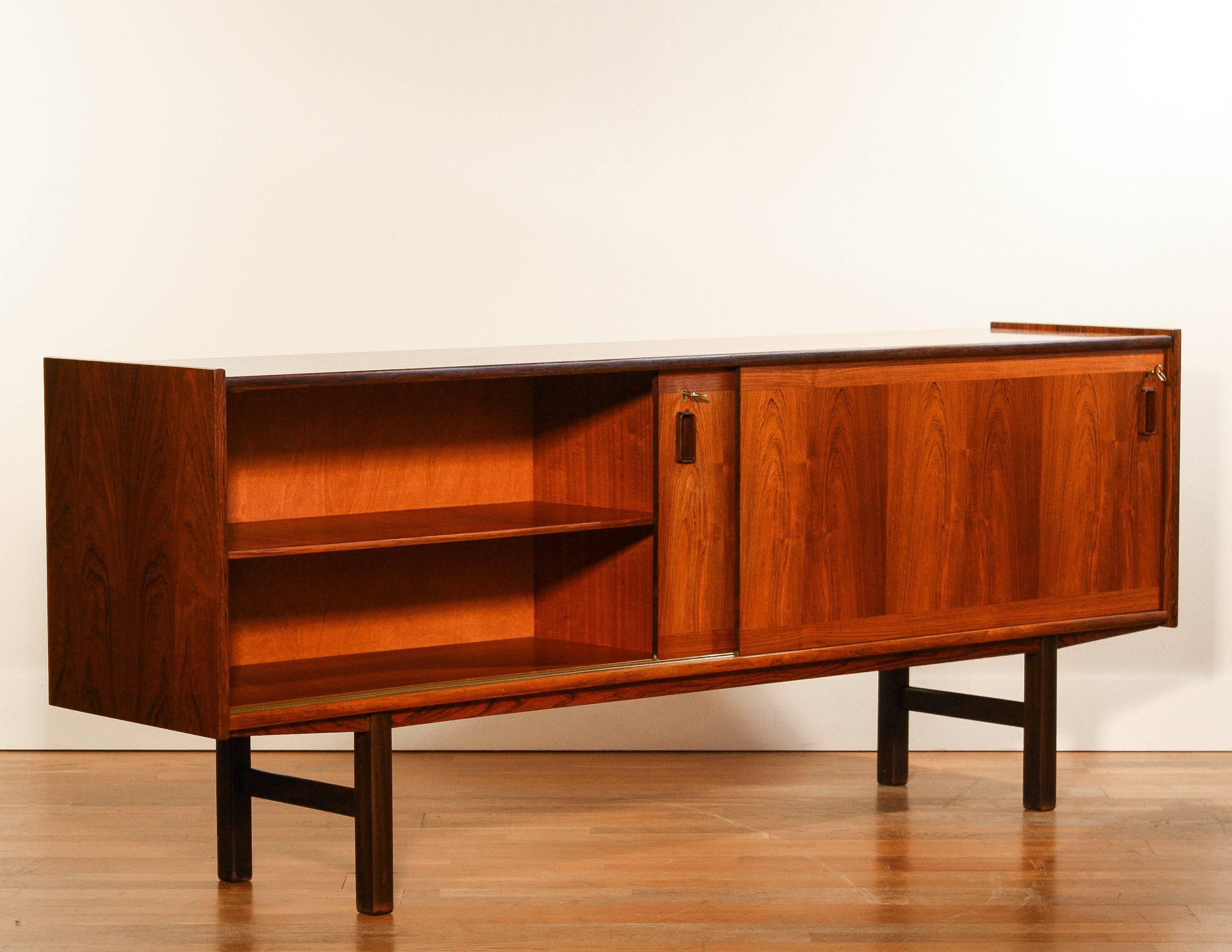 Beautiful sideboard in “Rio Palissander” rosewood veneer.
Two sliding doors and behind one of the sliding doors there are four drawers.
Original keys are included.

This sideboard is in excellent condition.

Designed by: Gunni