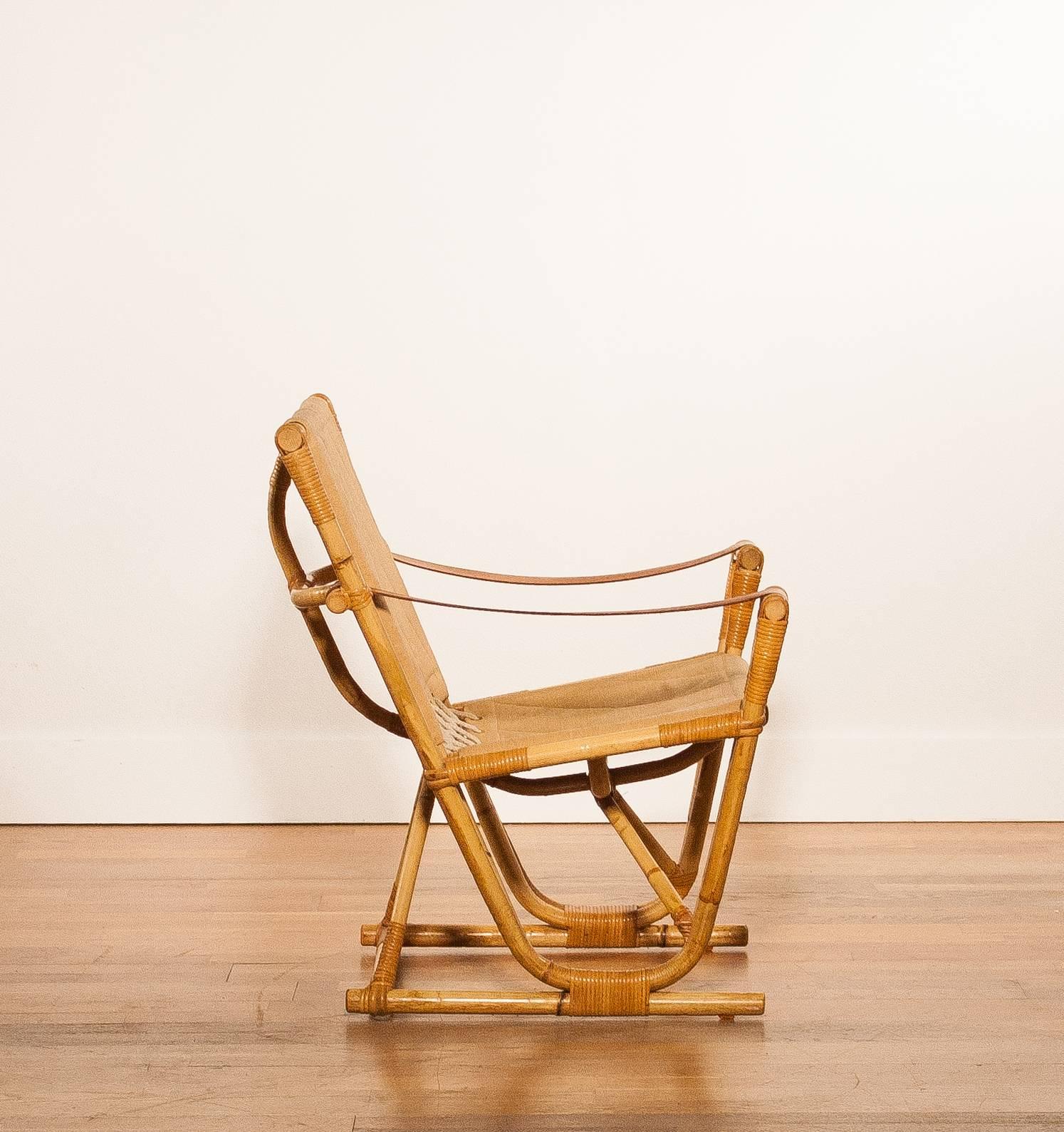 In absolute mint condition bamboo / rattan safari chair.

The linen / cotton upholstery and leather armrests are also in a perfect condition.

Period: 1950-1959.

The dimensions are:
74 cm. wide,
74 cm. height,
62 cm. depth,
seat height is