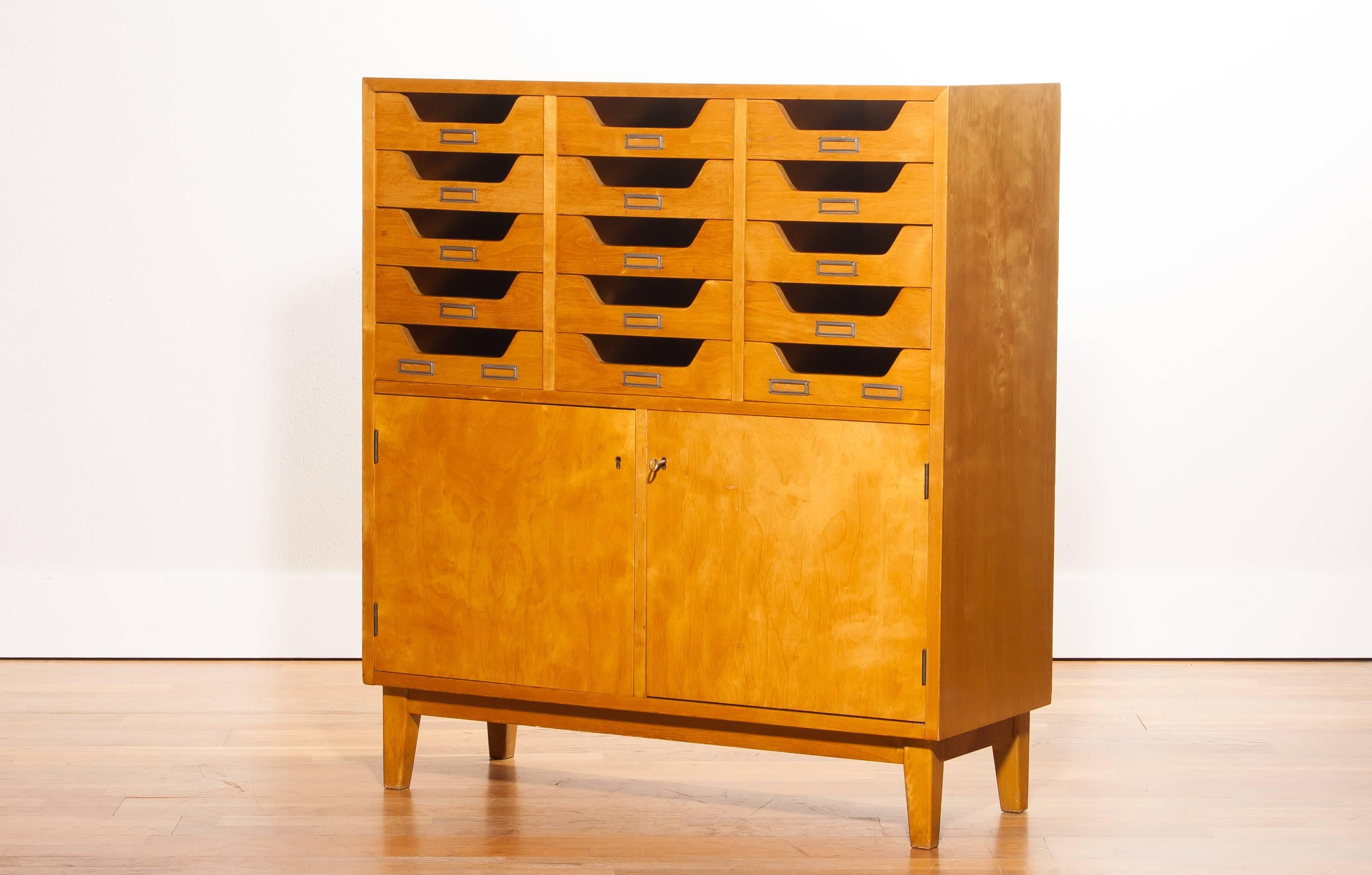 Very beautiful looking archive cabinet made by Jakobsson Industrier for Säffle Sweden.
The cabinet is made of elm and has 15 archive drawers and two doors.
It is in a very nice condition.
Period 1550s
Dimensions: H 100 cm, W 90 cm, D 35 cm.
