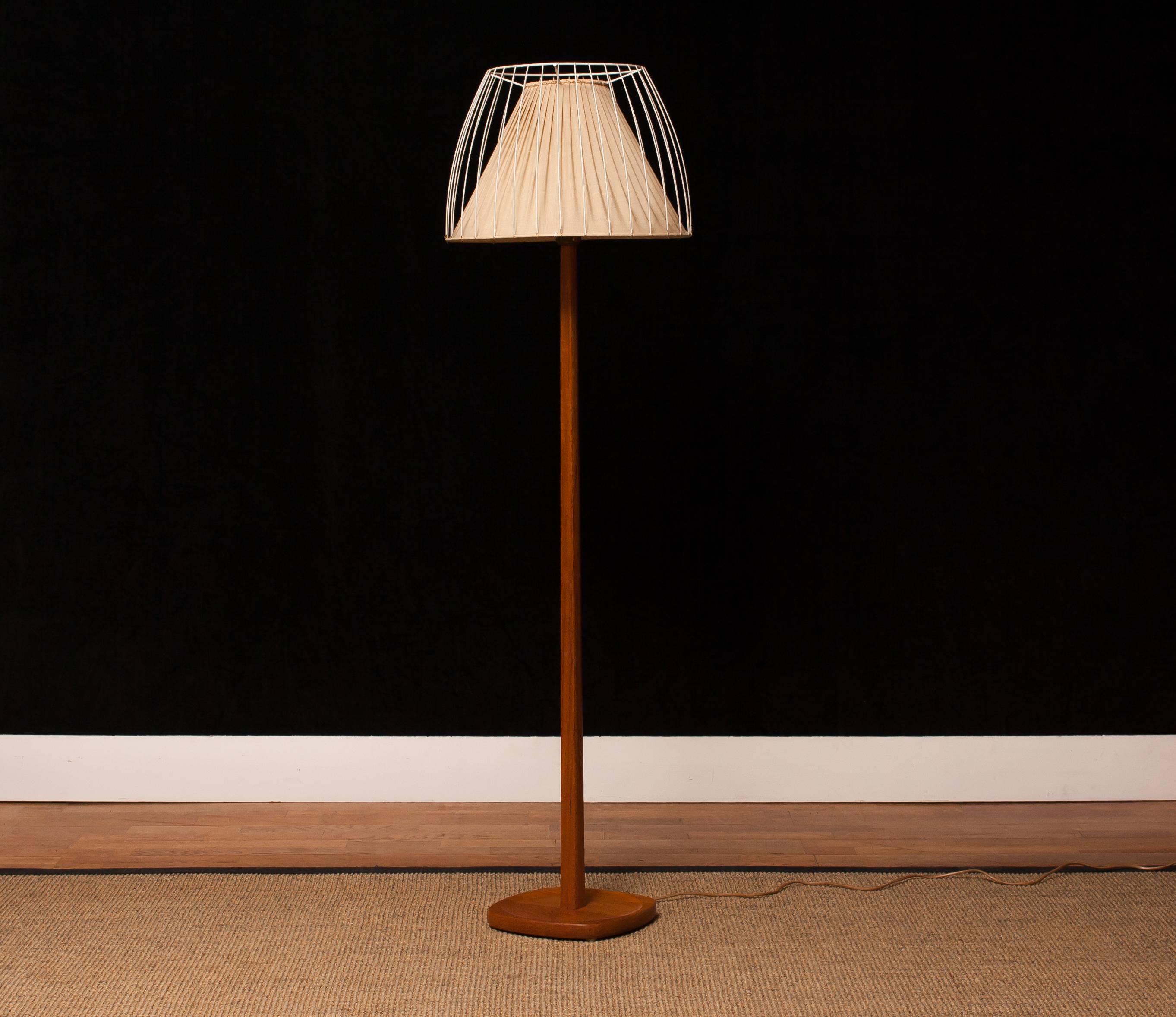Very beautiful floor lamp made by Stilarmatur, Sweden.
This lamp has a wonderful shape shade that consist a fabric shade on the inside and a open metal white lacquered shade on the outside on a very nice teak stand.
It is in a nice and working