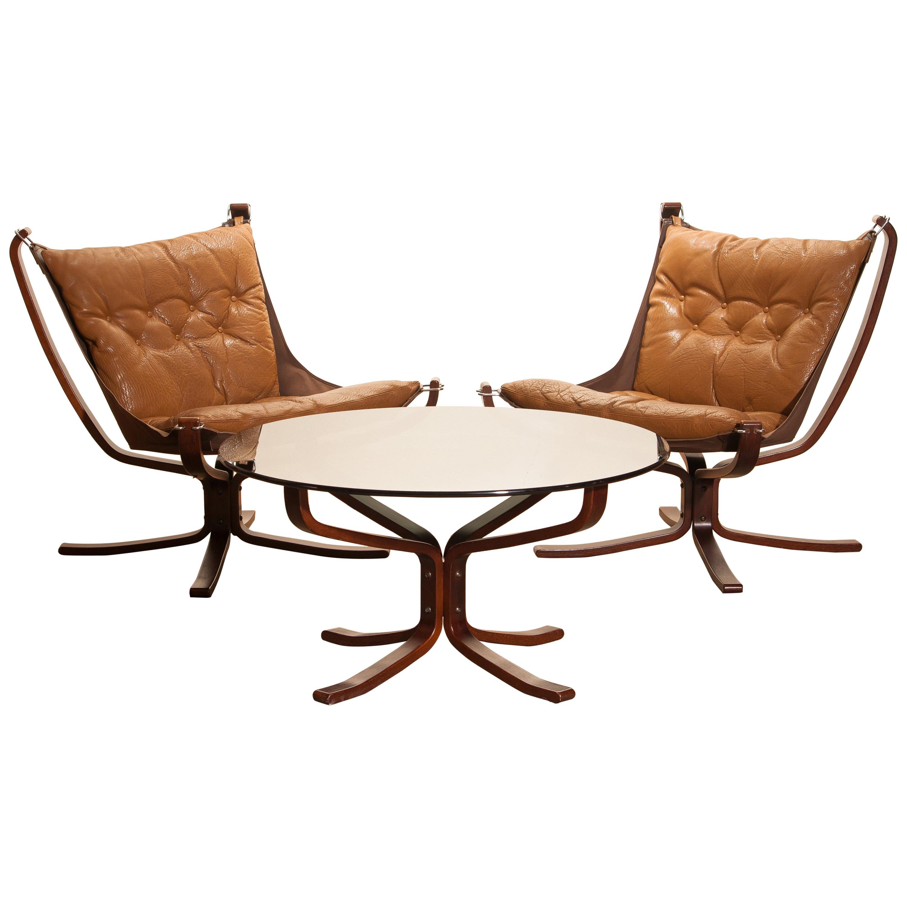 Extremely beautiful set of two 'Falcon' lounge / easy chairs complete with the original coffee table designed by Sigurd Ressell Norway.
The chairs and the table are in very good original condition.
The camel leather seating as the wooden frames