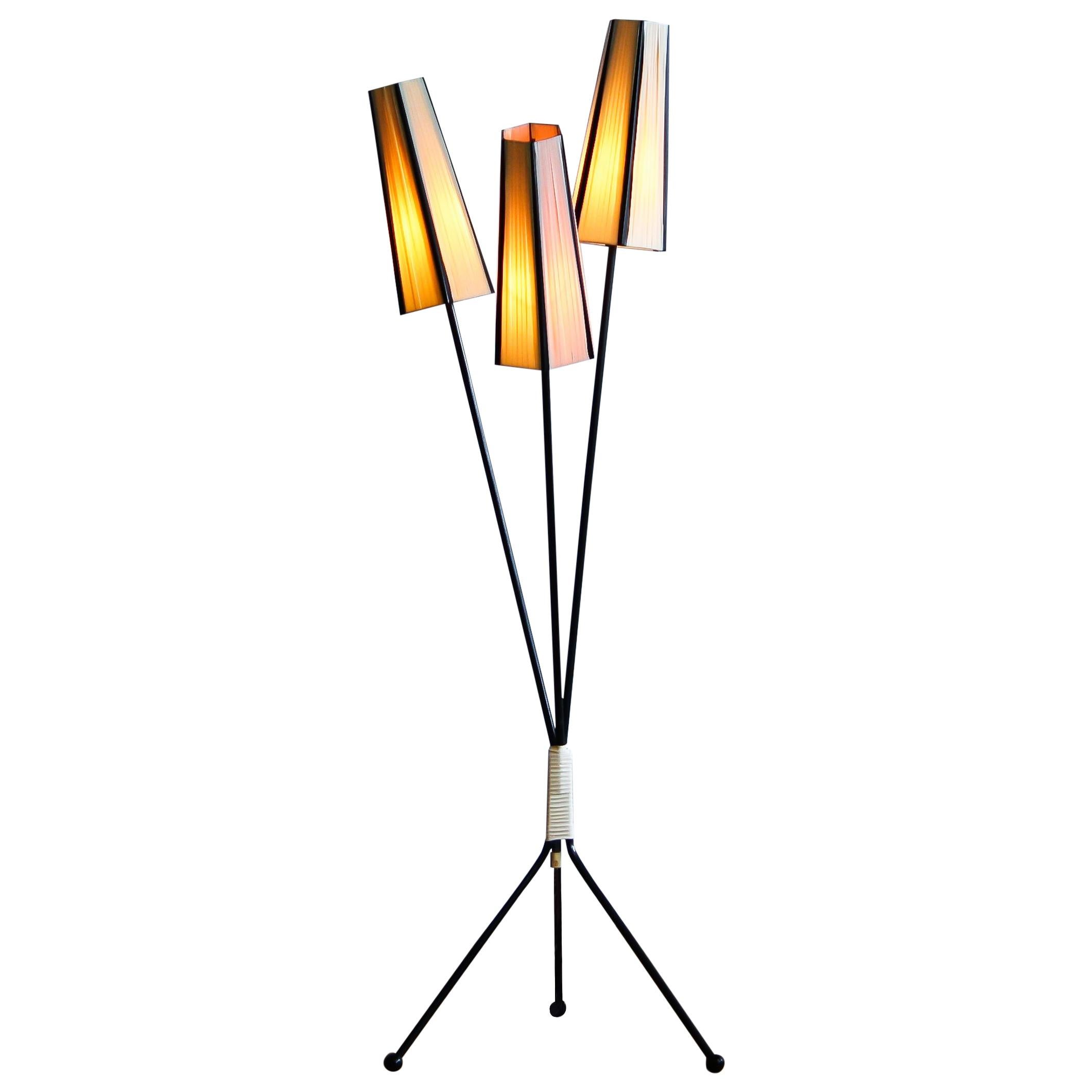 Floor lamp with two off-white and one salmon polyester fabrics covers from the 1950s.
The caps are lined with black cords.
The lamp stands on a black metal three-leg rest. It is in good condition.
Period 1950s.
Dimensions: H 138 cm, ø 45.