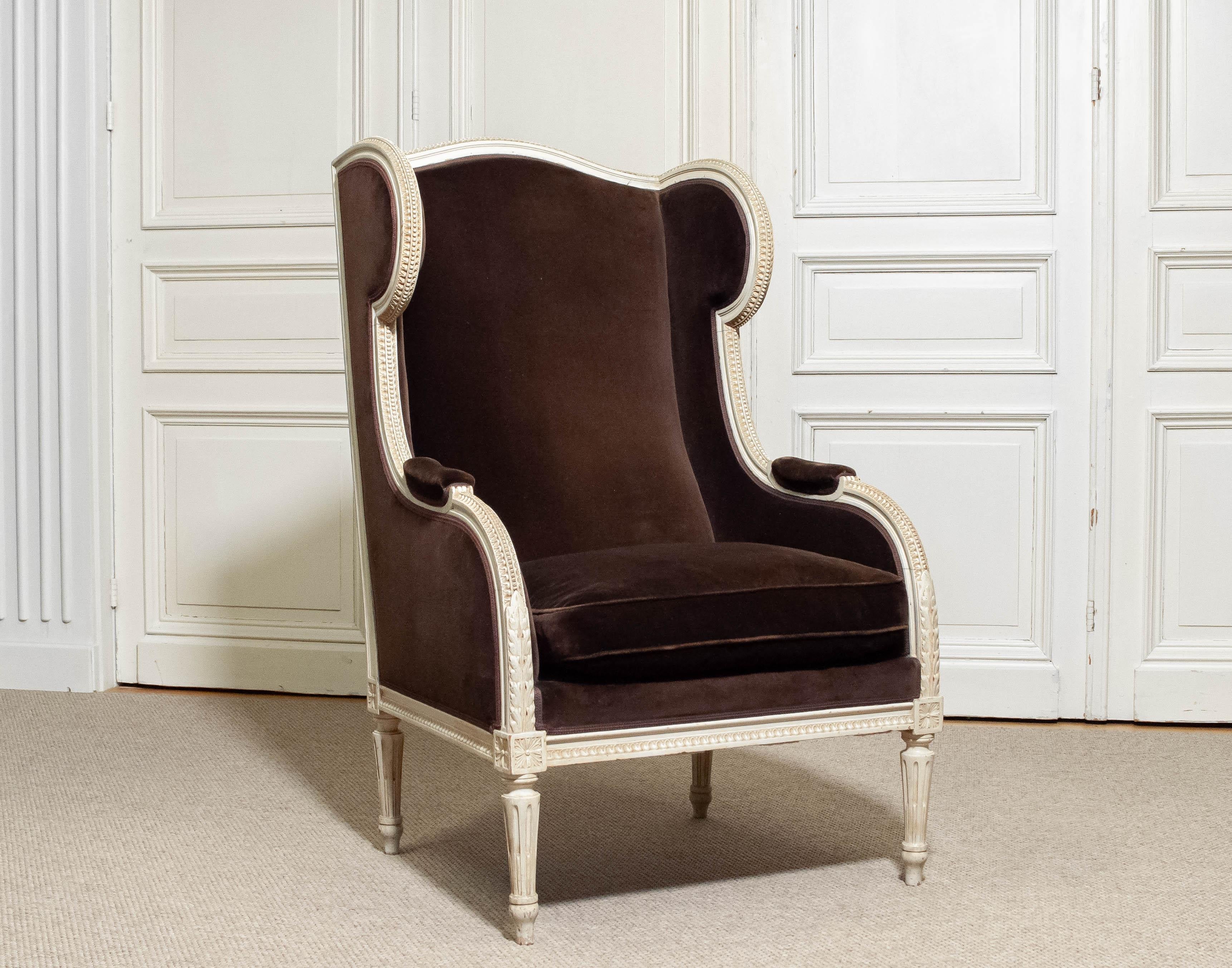 Fauteuil à oreilles de style Louis de France, tapissé de velours brun. Datant du 19ème siècle, avec une tapisserie plus récente. Cadre en bois sculpté et peint, récemment restauré avec de nouvelles sangles et de nouveaux ressorts. Les détails