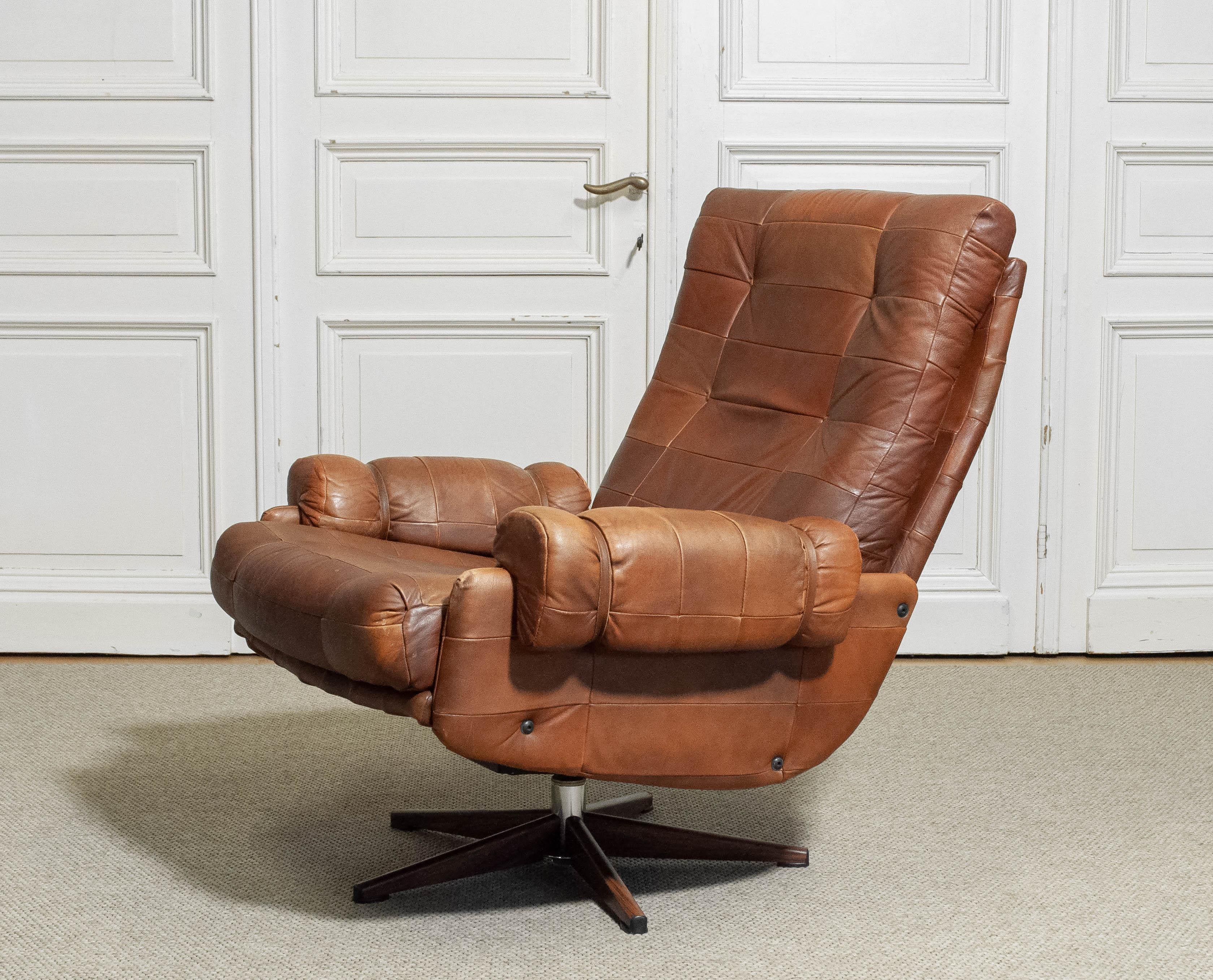Ce rare fauteuil à bascule et pivotant du milieu du siècle a été conçu par le designer suédois Arne Norells dans les années 1960. La chaise est recouverte d'un cuir patchwork richement patiné, présentant un motif de grille matelassé qui souligne sa