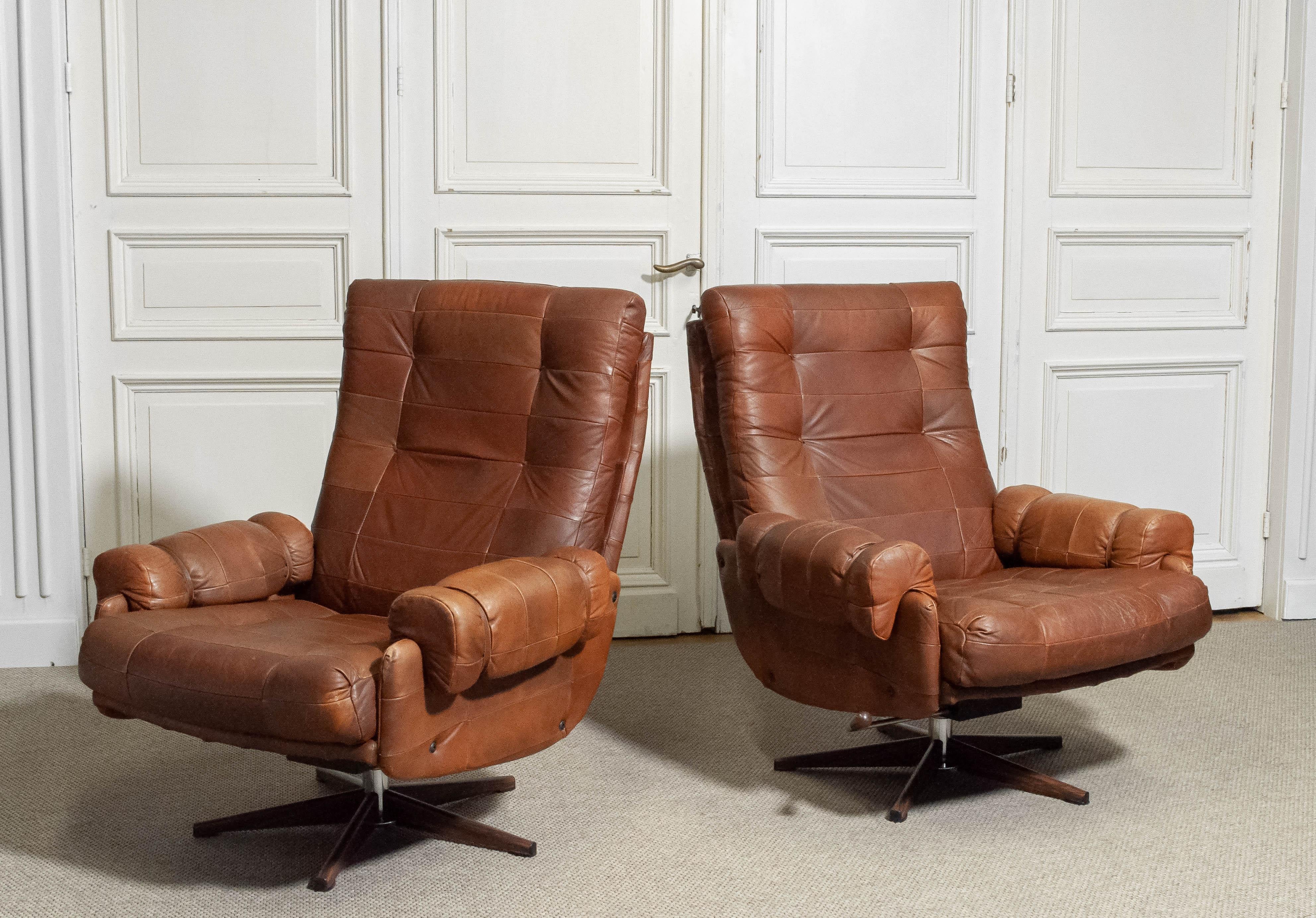 Queste rare sedie a dondolo e girevoli della metà del secolo scorso sono state progettate dal designer svedese Arne Norells negli anni '60. Le sedie sono rivestite in pelle patchwork riccamente patinata, con un motivo a griglia trapuntato che ne