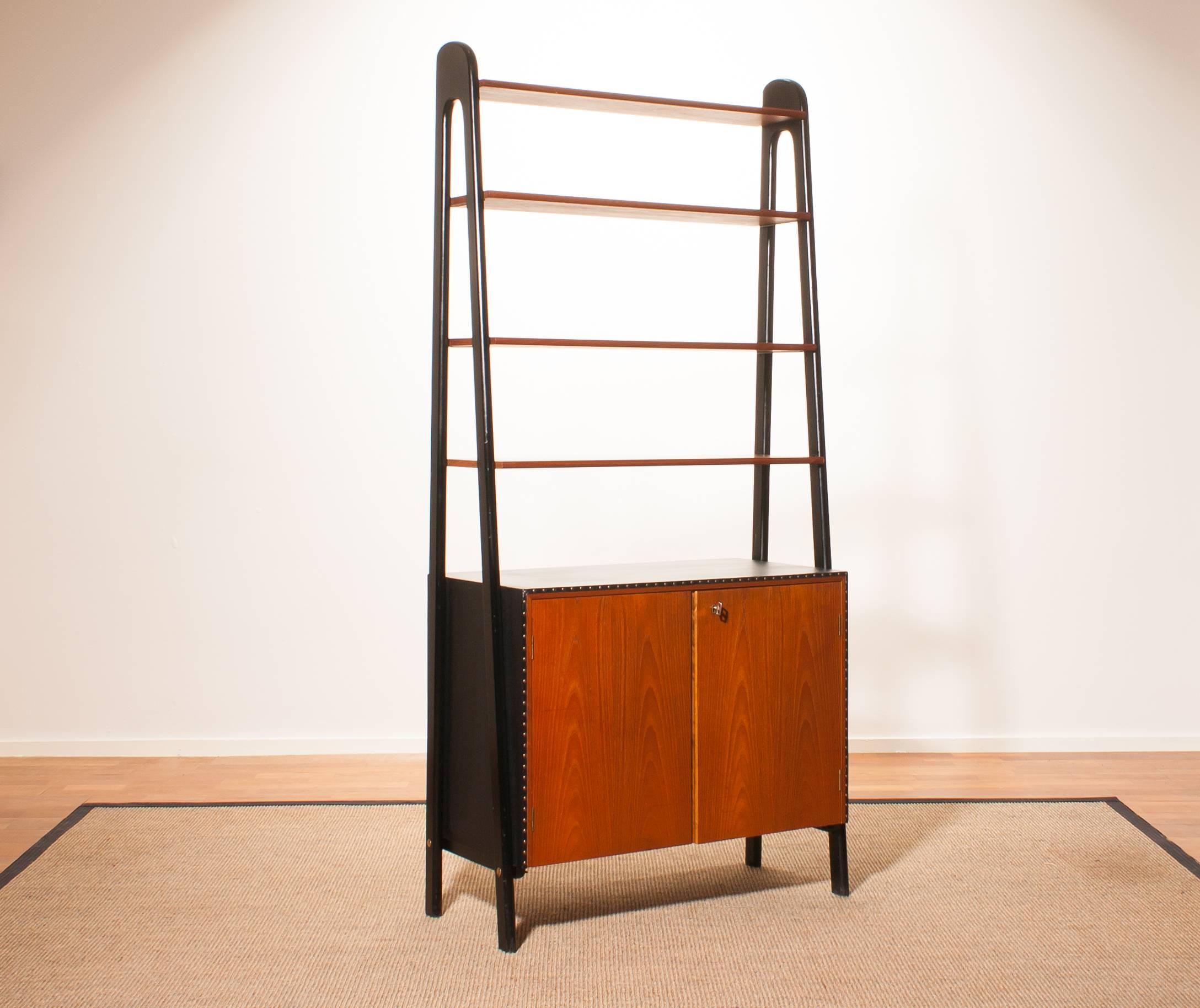 Beautiful bookcase by Bertil Fridhagen for Bodafors, Sweden.
This cabinet is made of teak and cupboard is upholstered with black leatherette.
Behind the doors there is a extendable writing top with a drawer.
It is in a excellent