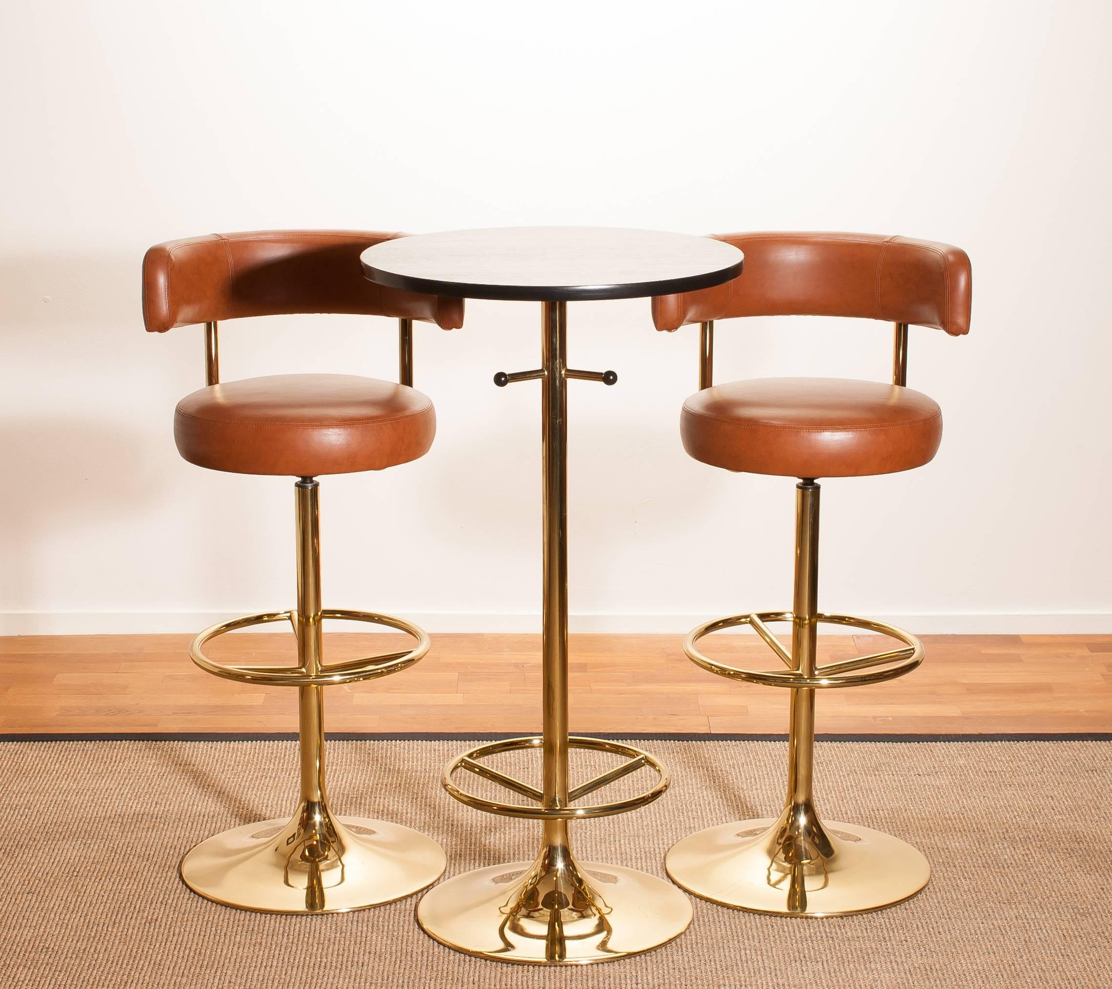 A magnificent set of beautiful bar stools and bar table designed by Börje Johanson for Johanson Design, Sweden.
The stools are very comfortable and look great with the combination of brass with new reupholstered cognac faux leather.
And also the