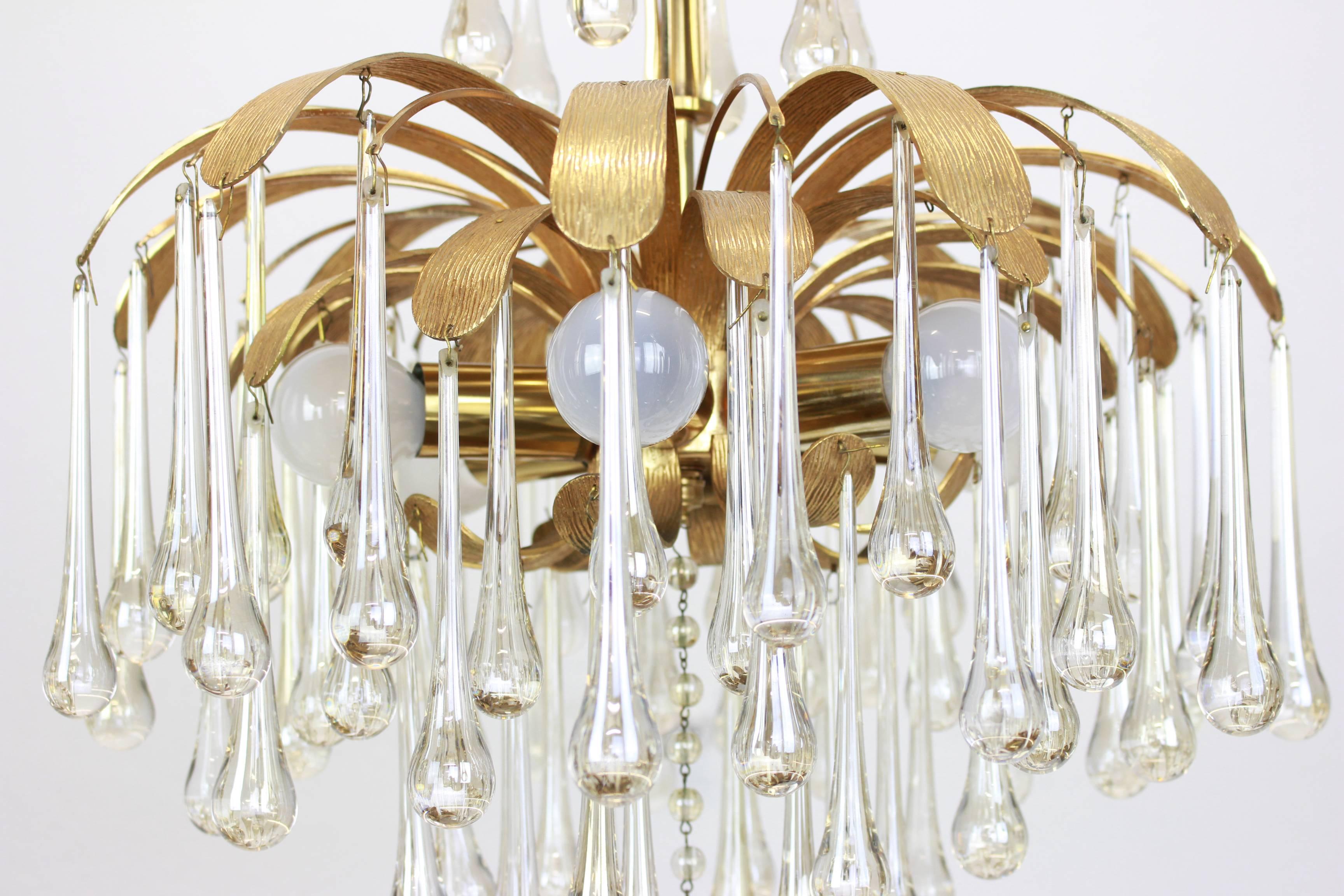 
A stunning chandelier by Palwa (Palme and Walter), Germany, manufactured in the 1960s. It’s composed of Murano teardrop glass pieces on a gilded brass frame with a Brutalist relief.


High quality and in very good condition. Cleaned, well-wired and