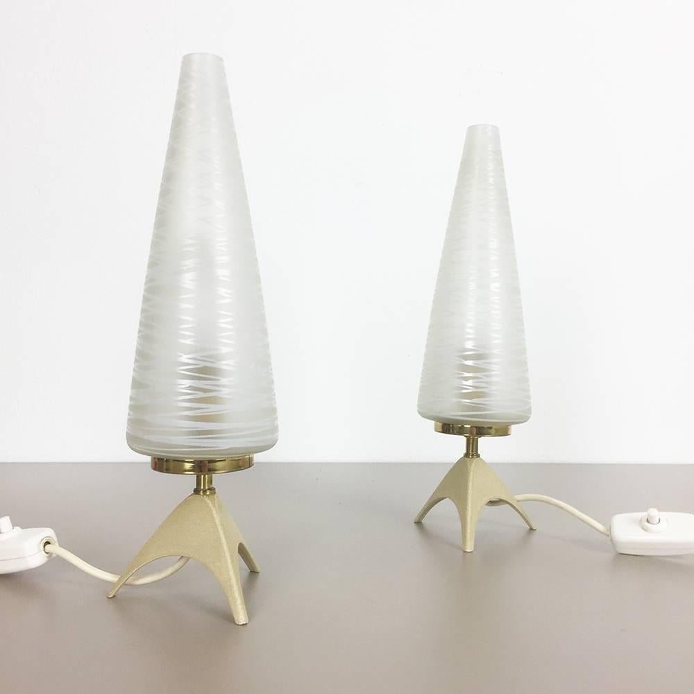 Set of two modernist tripod table lights.

origin: Germany,

1950s.

Original 1950s table lights made in Germany. This wonderful set of two modernist 1950s table light comes with a huge glass tube shade, and lovely formed beige metal tripod