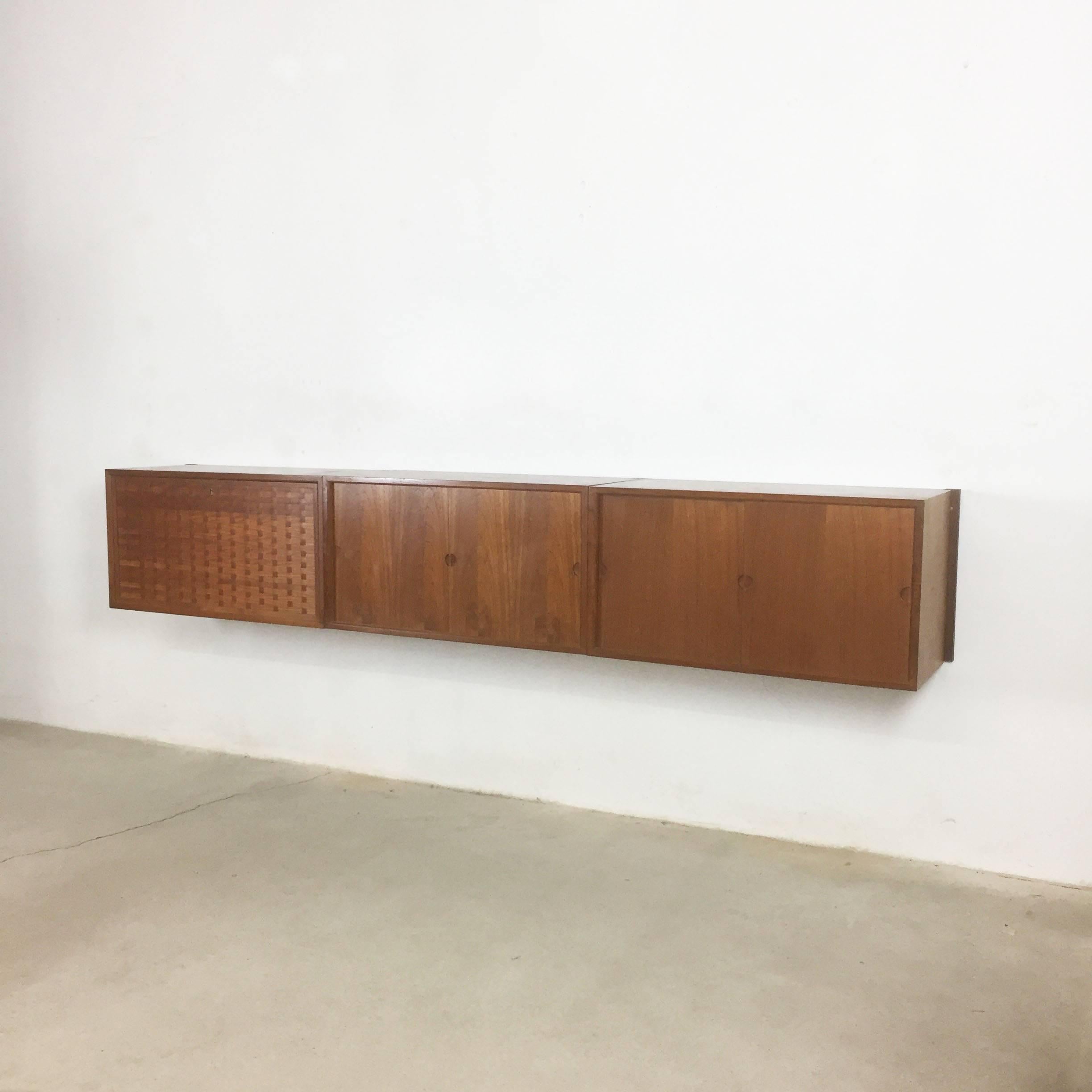 Original Danish wall unit designed by Poul Cadovius in the 1950s for Cado, Denmark. This listed unit was produced by Cado in Denmark in the 1960s. This unit consists of three cabinet elements hanging on four wooden teak wall holder. Two elements are