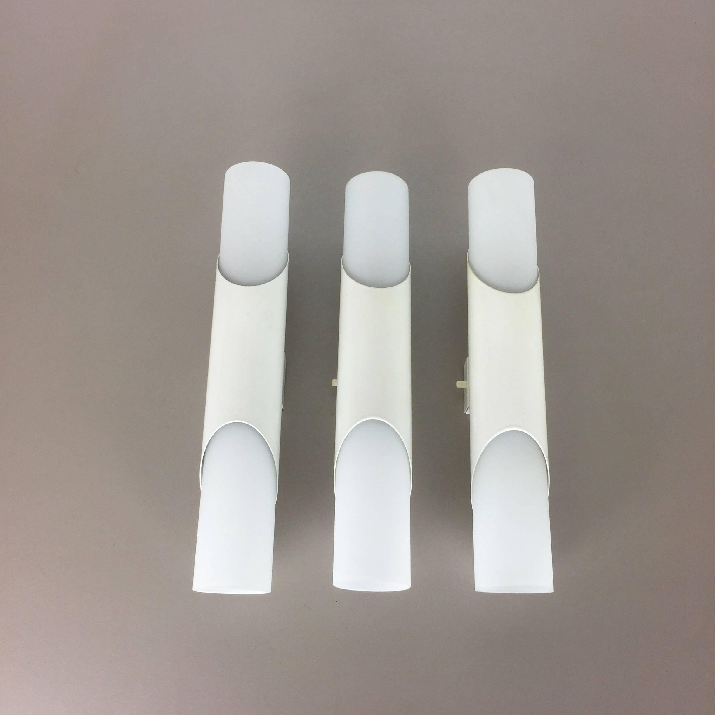 Set of three wall lights with glass tubes.

Origin: Germany, 

1970s.

This set of three original 1970s RAAK style modernist wall lights feature white-lacquered metallic wall plates and frosted glass shade tubes. Each light has a switch and