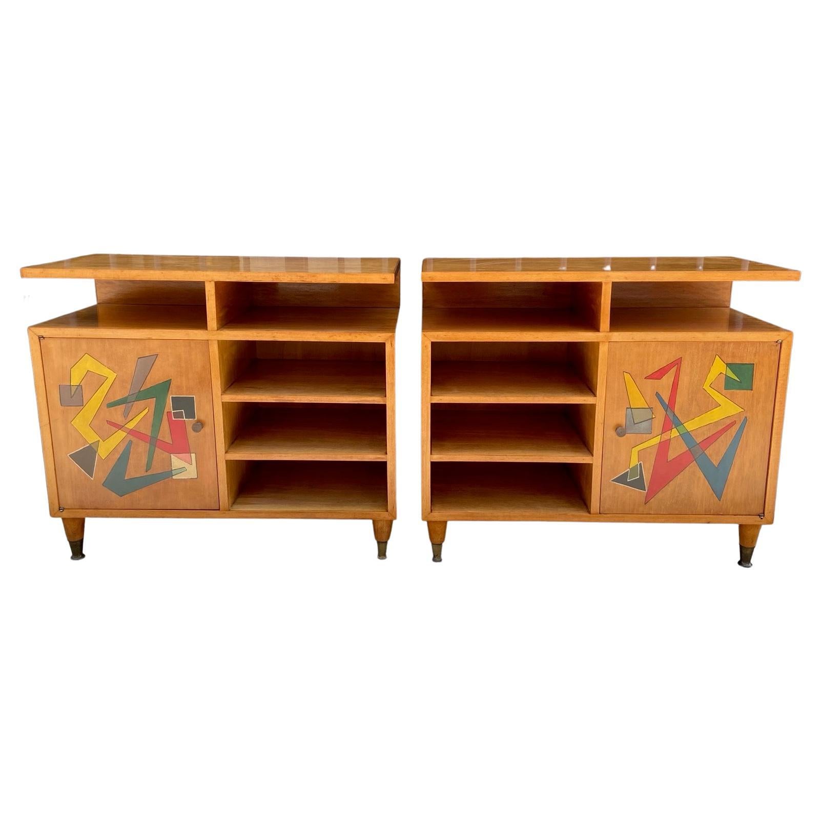 An original, unique and unusual 1950's Italian pair of blond wood cabinets or night stands with colourful abstract painted doors, shelves, brass sabots and handles. Solid, good design and quality. 
 