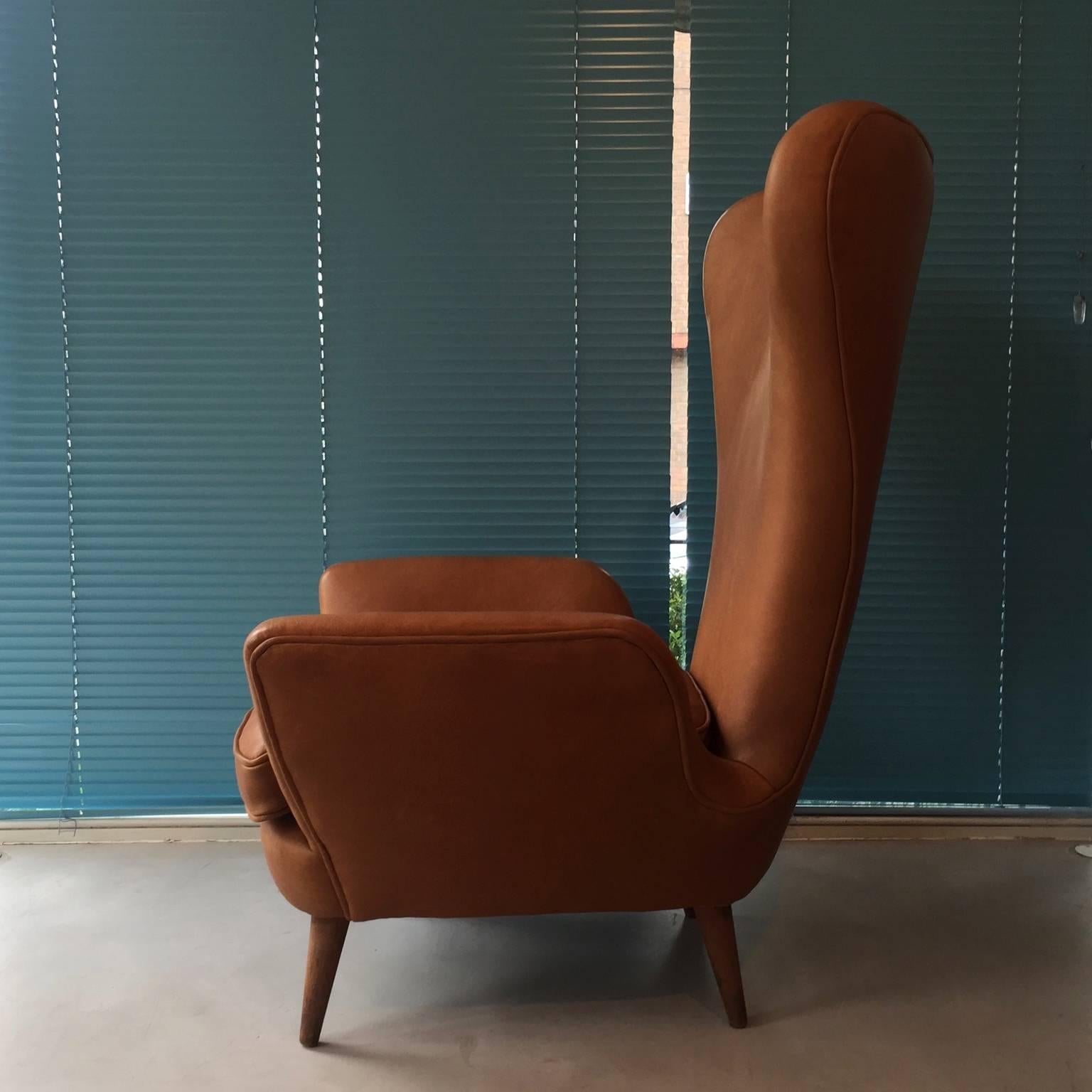 Two 1950's sculptural leather armchairs, reupholstered in an untreated tan leather.
