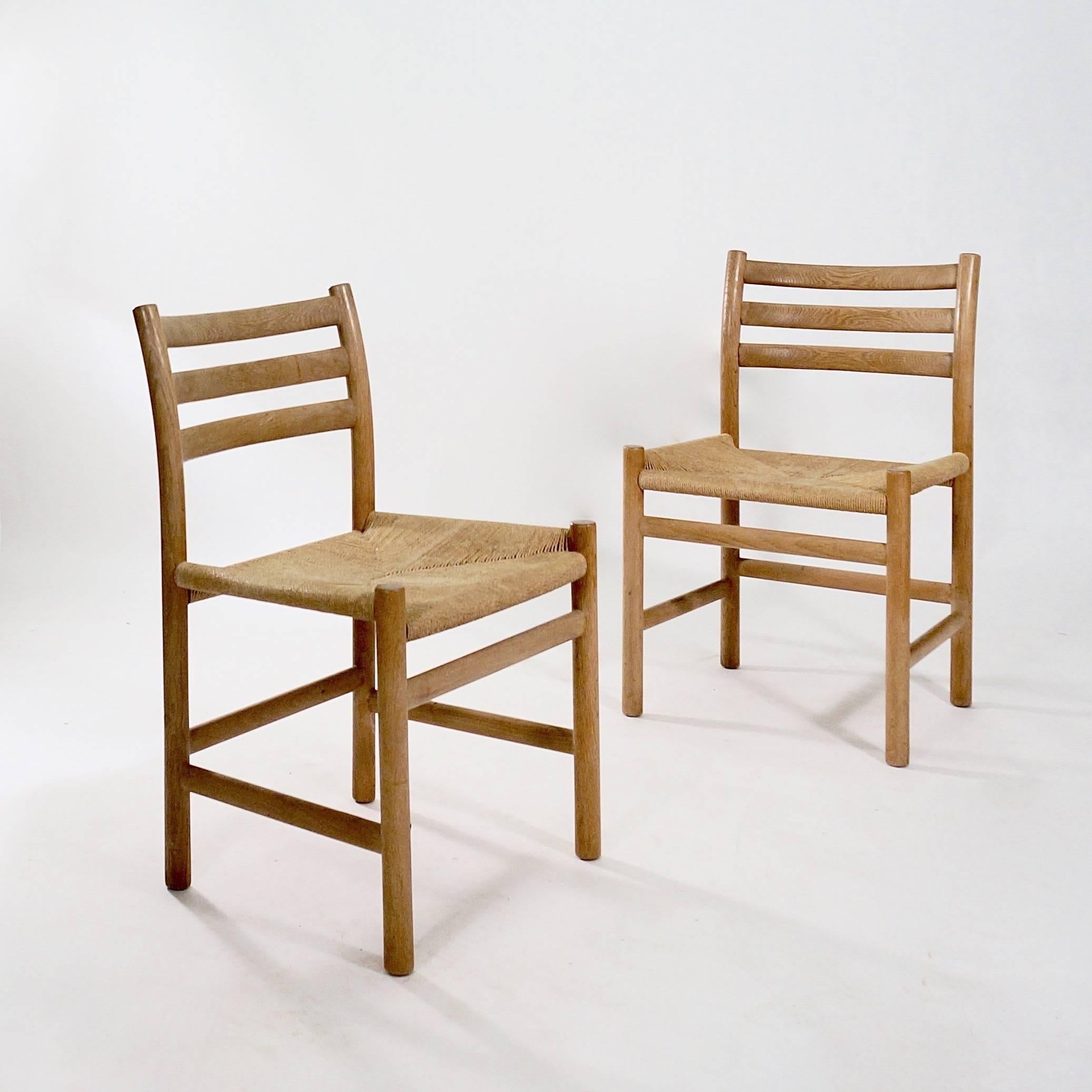 A set of four quarter-sawn oak ladderback dining chairs each with simple turned legs joined by stretchers supporting a raked and dished ladderback and a seagrass seat,

Denmark, circa 1950s.