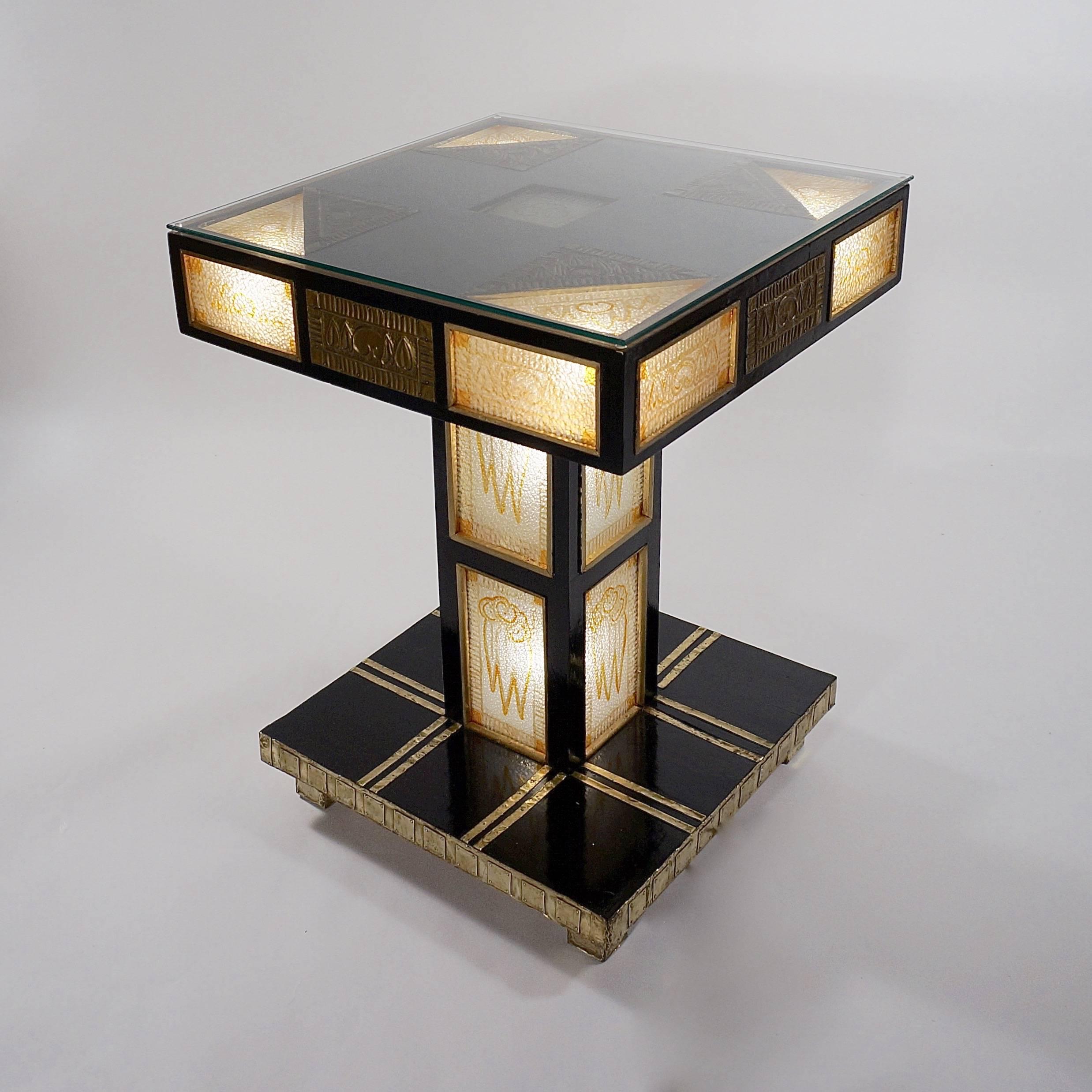 The square top with gold painted textured glass panes and repousse gilt brass mounts set in an ebonized wooden frame supported by a column with glazed panels on a square plinth base. Wired for electricity,

Vienna, circa 1910.