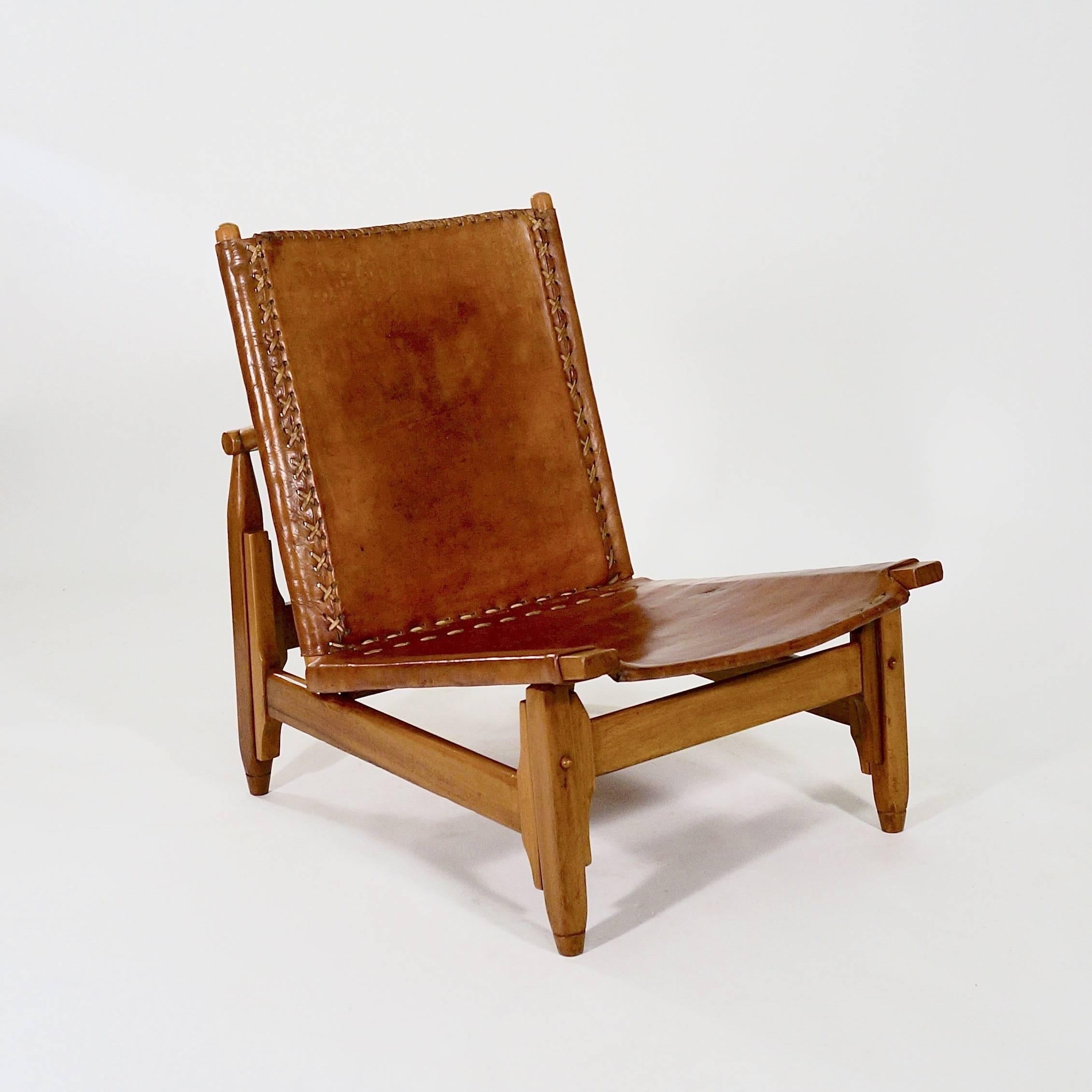 Each with a walnut frame, supporting saddle-stitched tan leather raked back and angled seat. With adjustable supports to allow movement in the leather.

Probably, Sweden, circa 1940s.