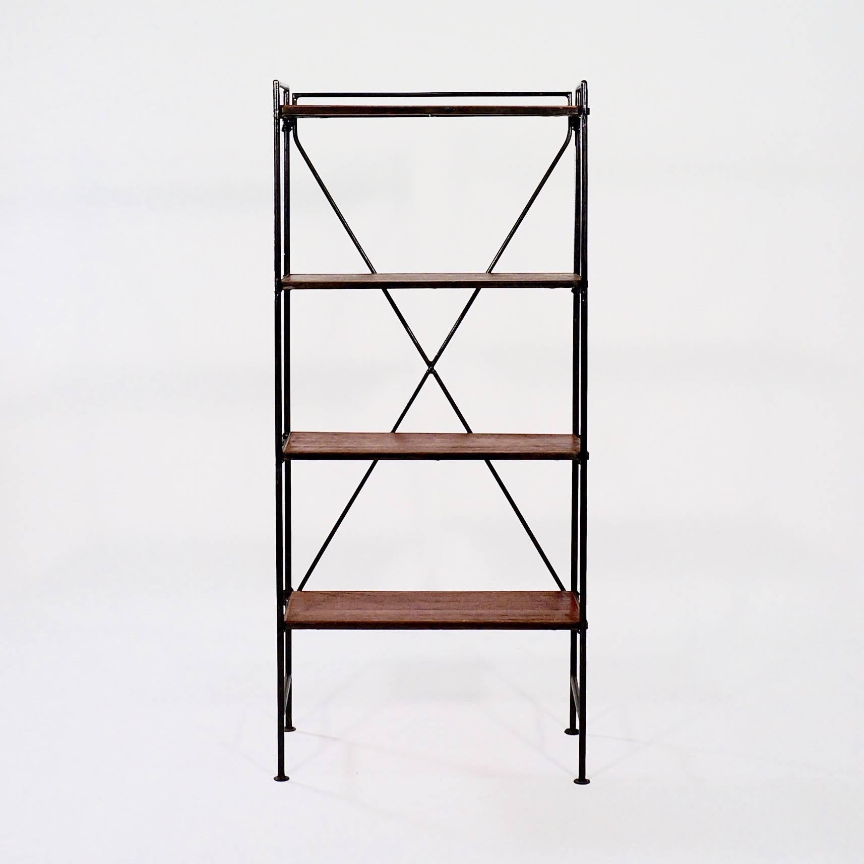 The collapsible ebonized wrought iron frame with four disc feet supporting four hinged teak shelves,
 
France, circa 1940s.