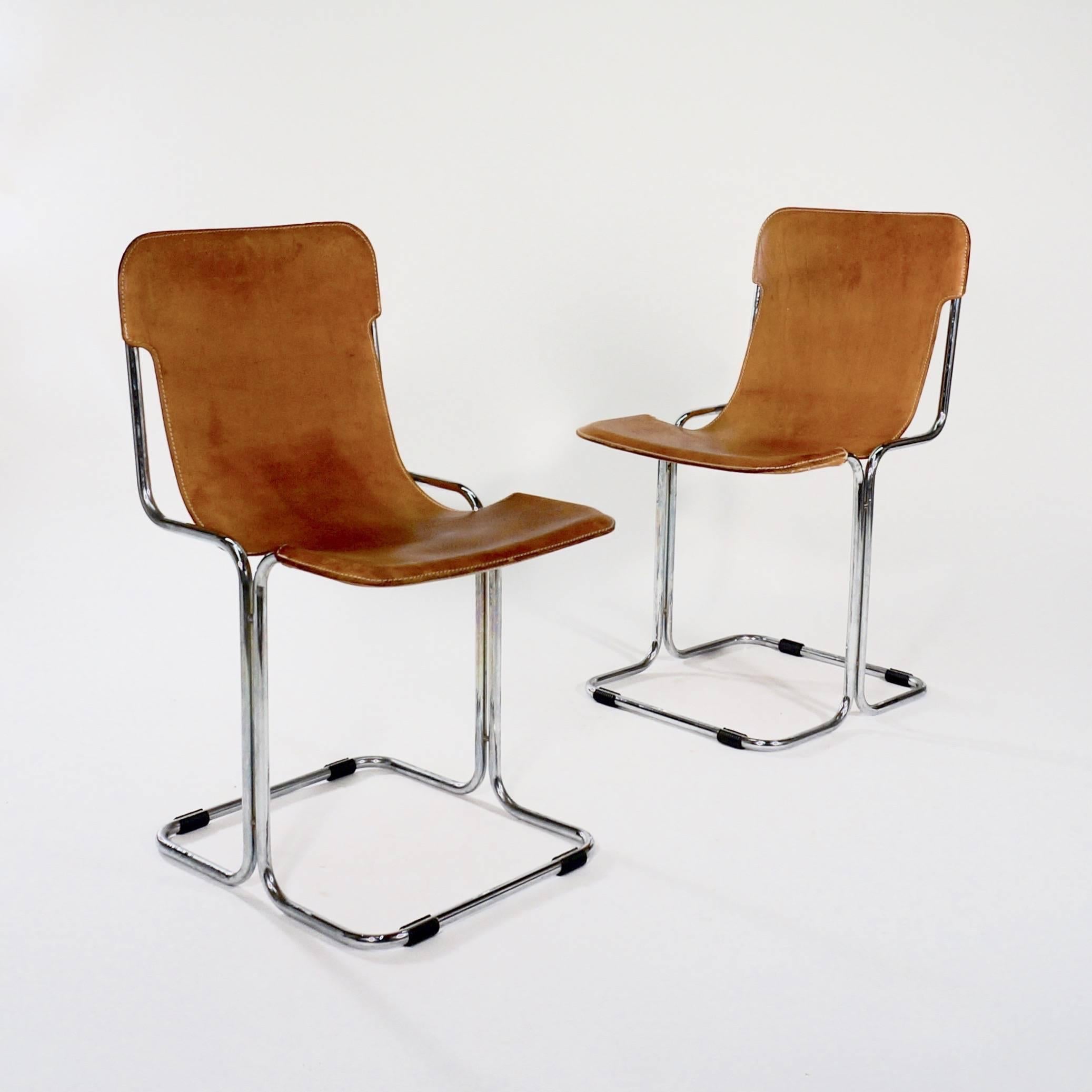 The continuous tubular chromed metal frame with a single tan leather slung back and seat. The base with removeable plastic floor protectors, 

Denmark, stamped 24 AGO 1973 to the undersides.