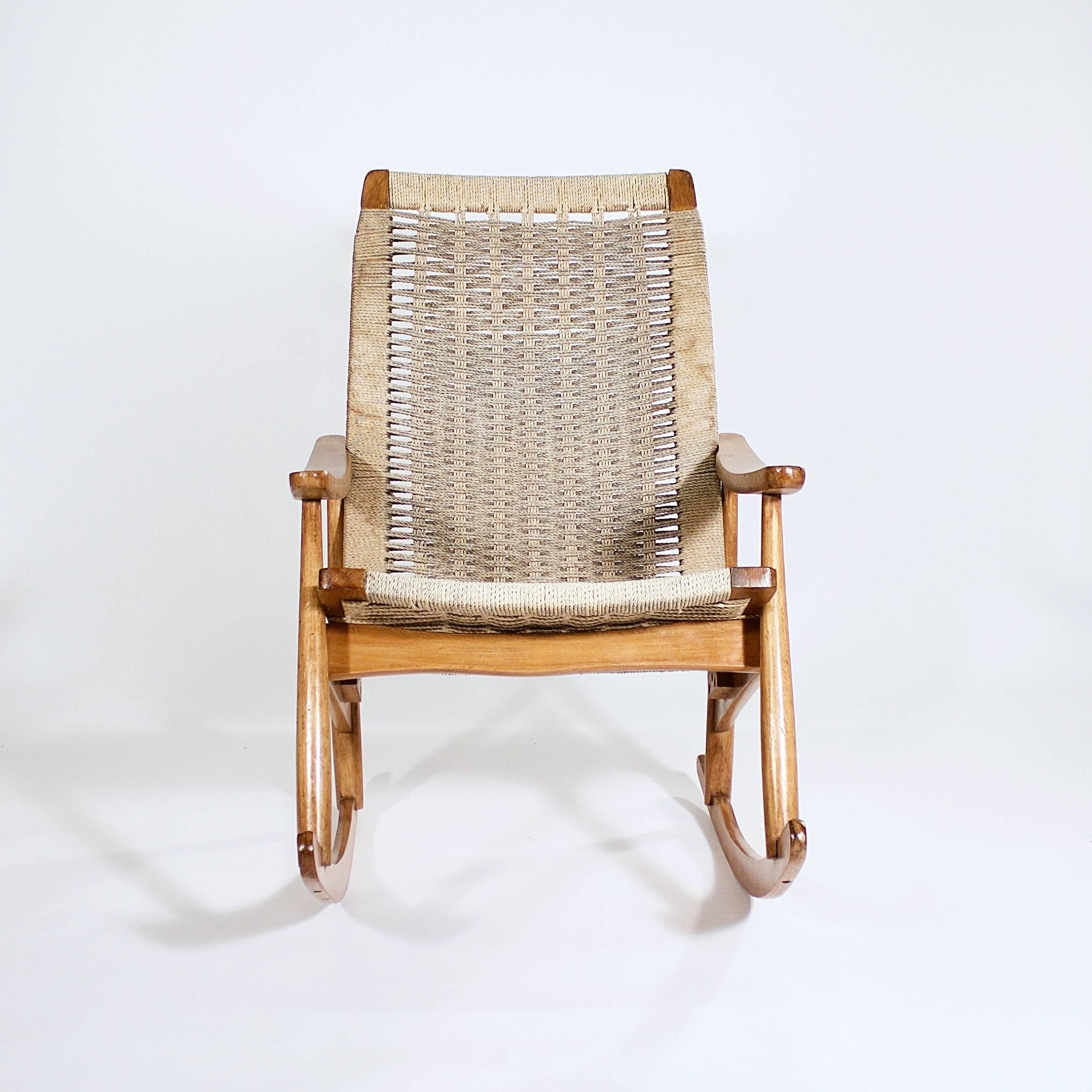 The raked back and seat with woven cord supported by a teak rocking frame with curving arms,

Denmark, circa 1950s.
