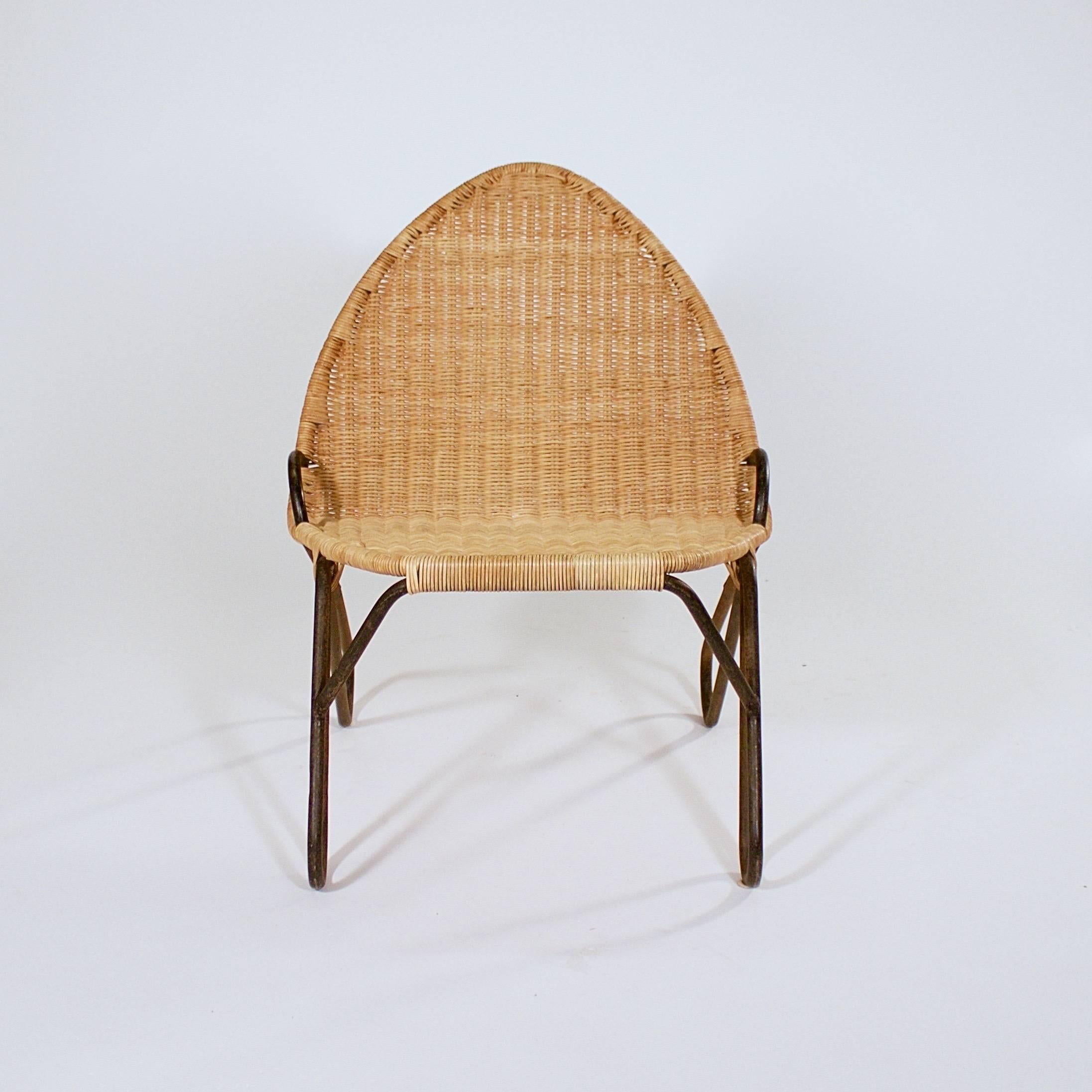 The caned seat and arched back supported by a continuous bent iron frame.

Sweden, circa 1950s.