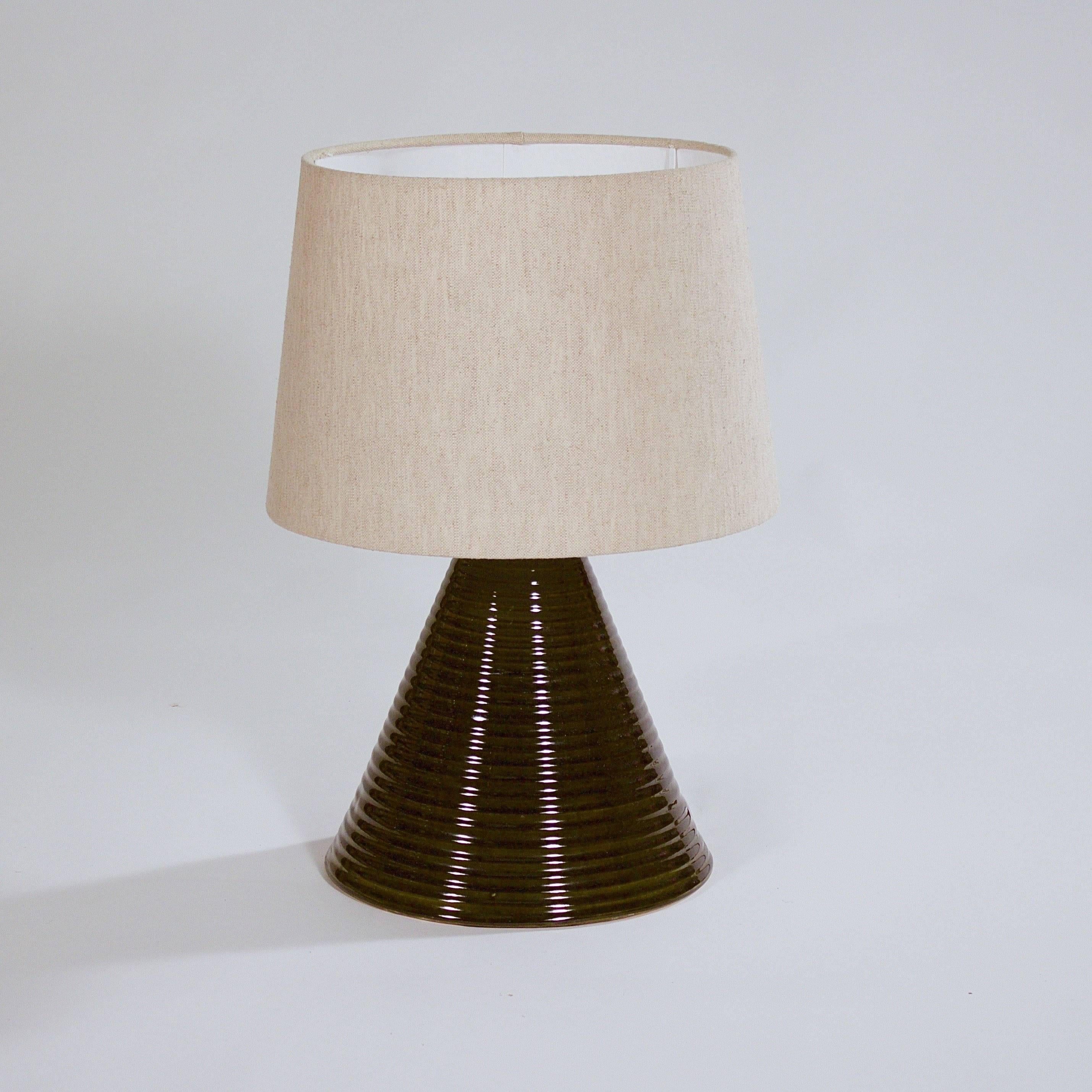 A stoneware cone shaped table lamp with a ribbed body and deep green glaze.

Designed for Rorstrand. Sweden, circa 1960s

Dimensions do not include the shade. Shade not included in the sale.