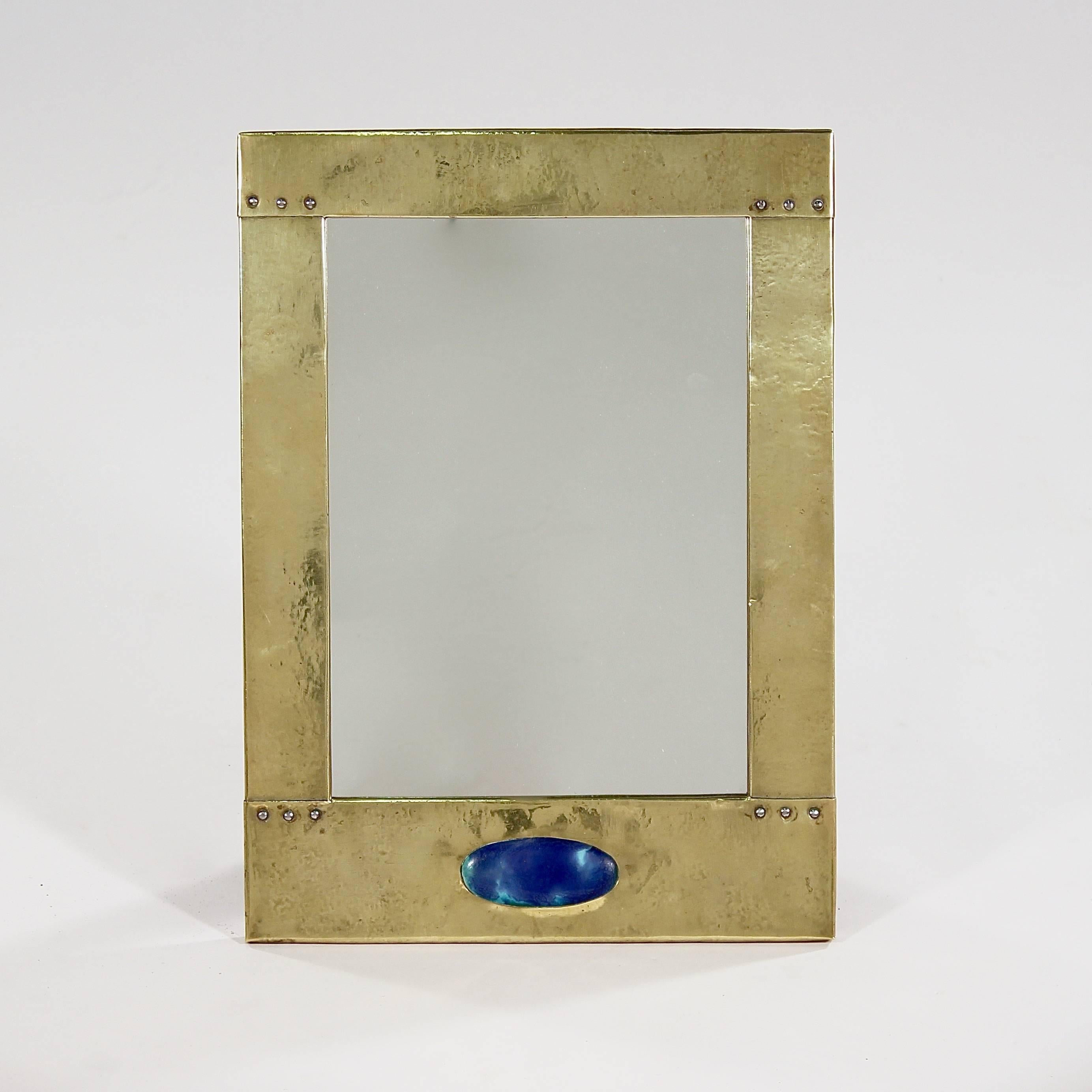 The brass clad rivetted frame with a central oval Ruskin Cabochon to the bottom.

England, circa 1910.