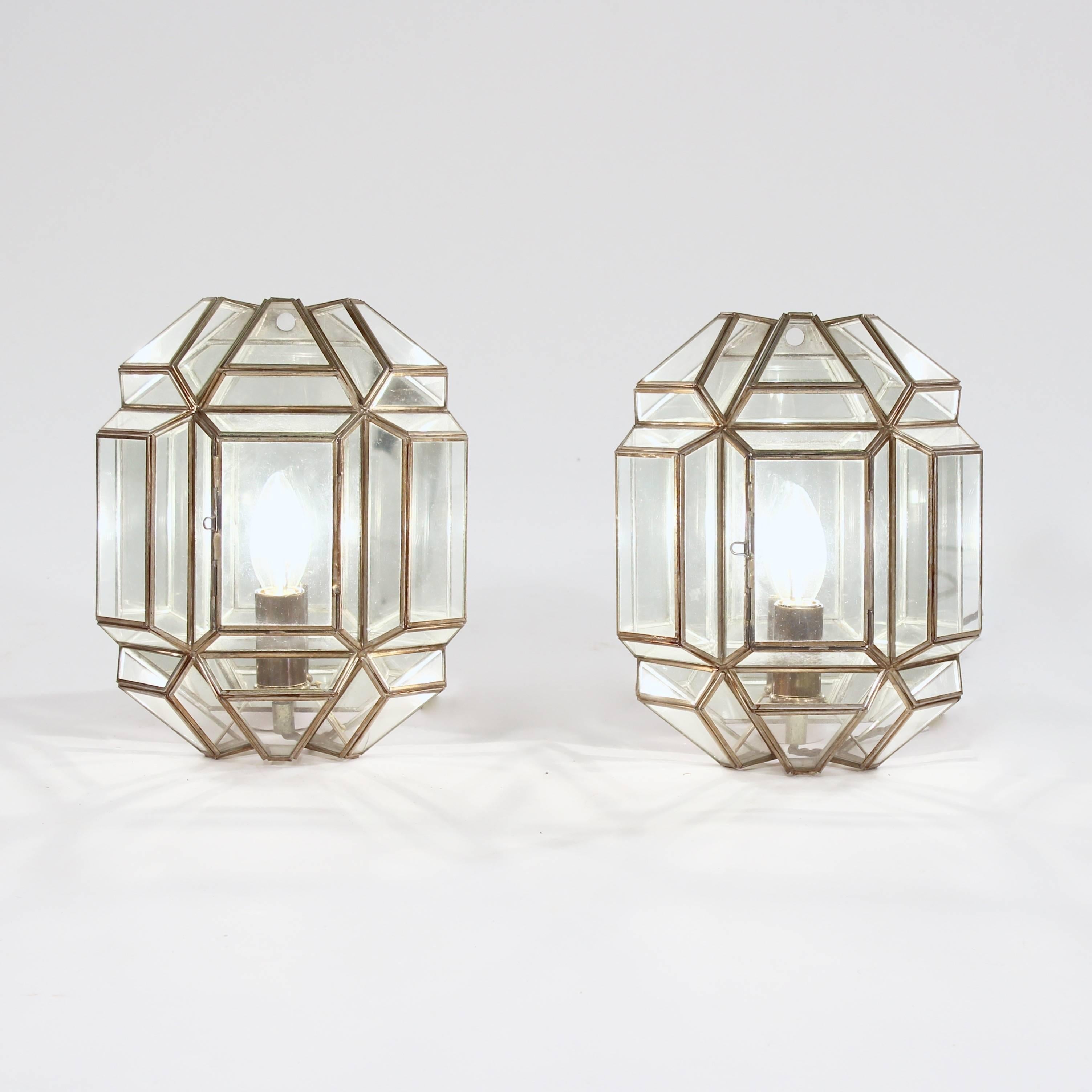 Each with a glazed facetted cage frame with brass edging enclosing a bulb and a mirrored back.

Manufactured by Taurus.

Spain, circa 1970s.