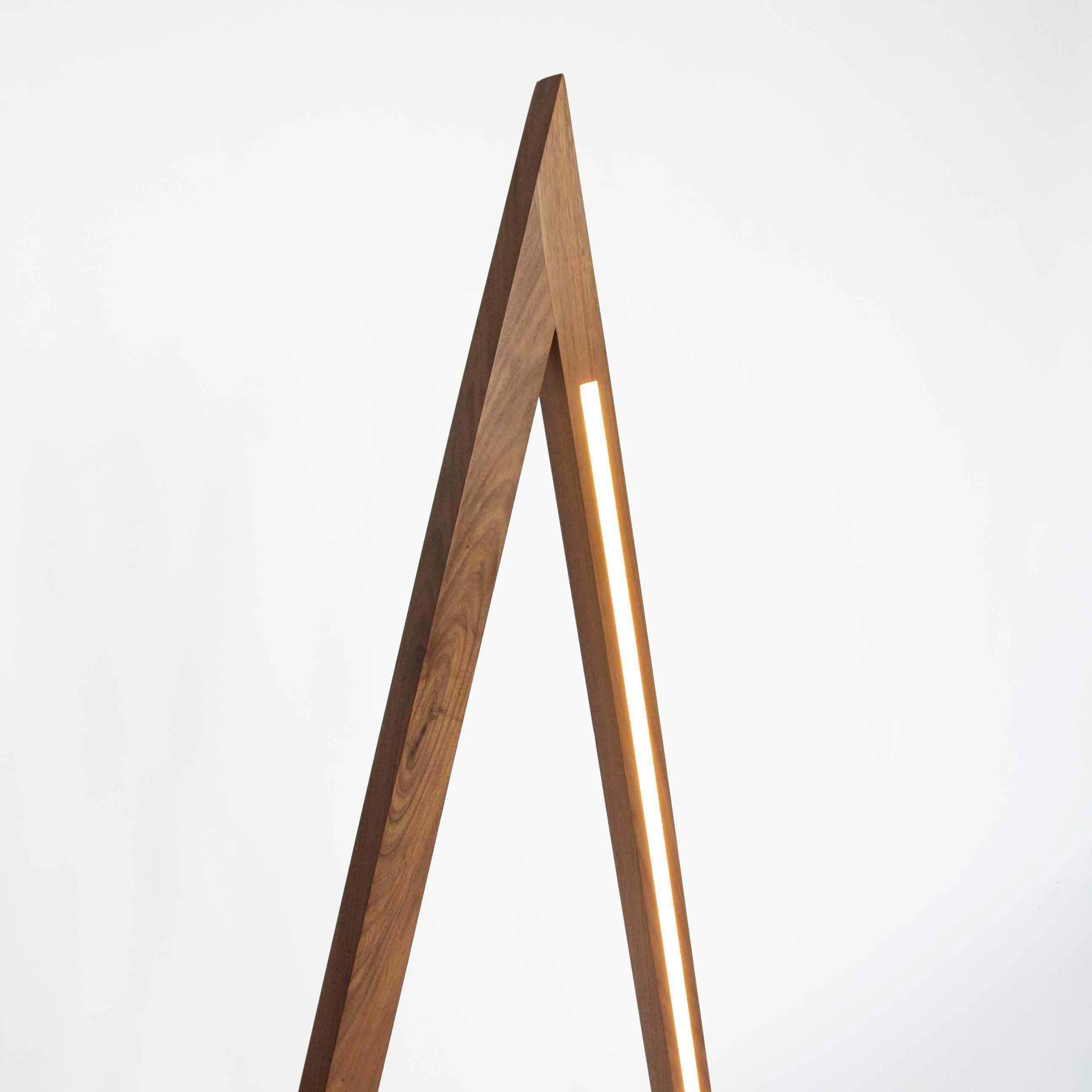 Fort Makers' Tall Skinny Triangle Walnut Line Light is made in Brooklyn by Noah Spencer. This sculptural LED light juxtaposes hard lines with soft reflected light and emits an ambient aura. The lifespan of an LED strip is approximately 50,000