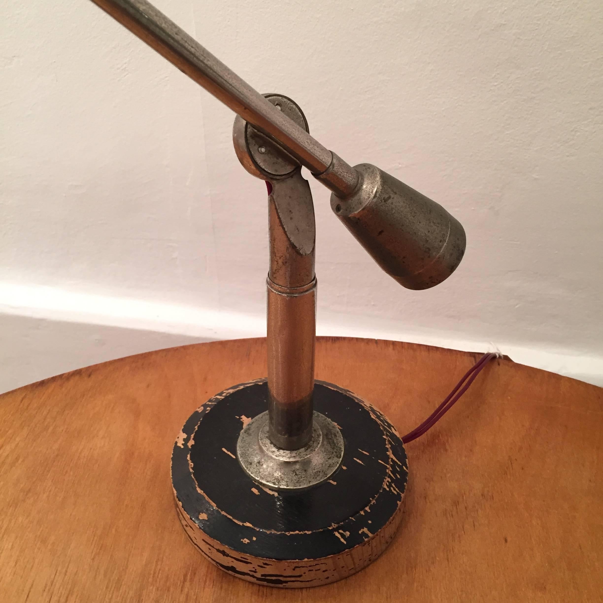 This vintage table lamp was designed by Edouard Wilfred Buquet and produced by SGDG Paris in 1927. It is made from aluminum and fixed to a wooden base that features the makers label.
