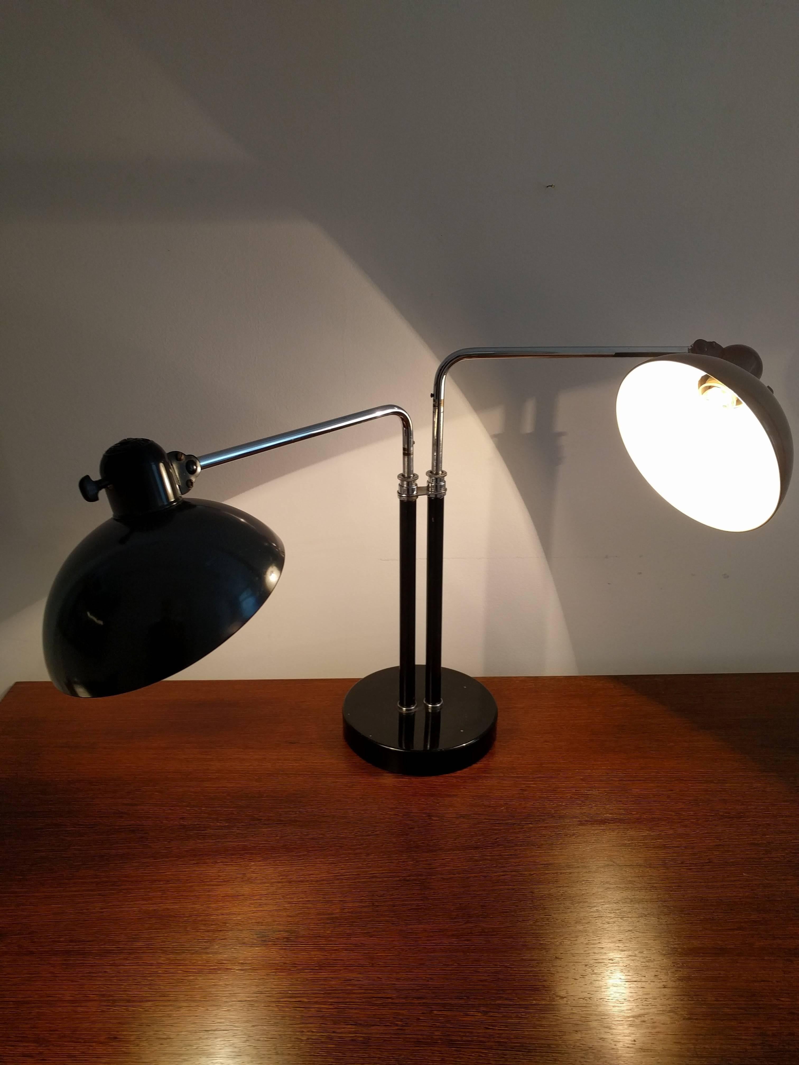 This table lamp was designed by Christian Dell and produced by Kaiser Idell in the 1930s. It is made from chromed steel and black sheet metal. The lamp features two lamp shades and is still in its original condition.