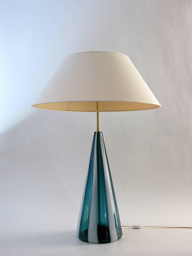 A big fasce verticali lamp in blue glass with white stripes in the style of Fulvio Bianconi for Venini.
The hardware in brass.
 
High: 85.0cm with shade
High: 50.0cm only the glass, without shade
Diameter glass: 20.0cm
Diameter shade: 60.0cm
