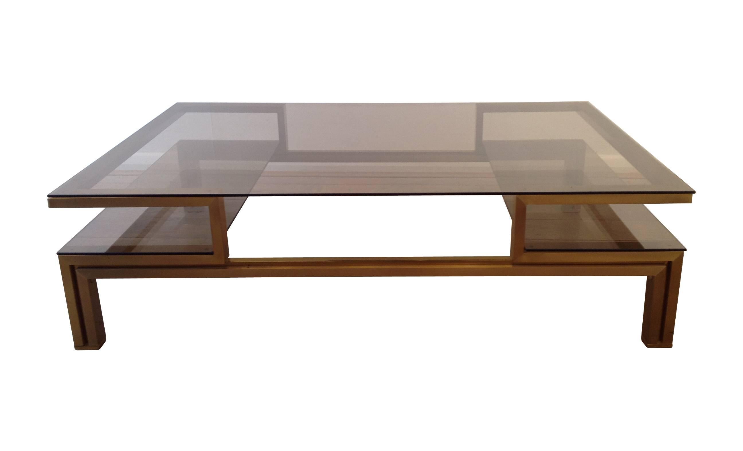 A Guy Lefevre gilt metal and brass coffee table, with smoke glass top and side shelves.