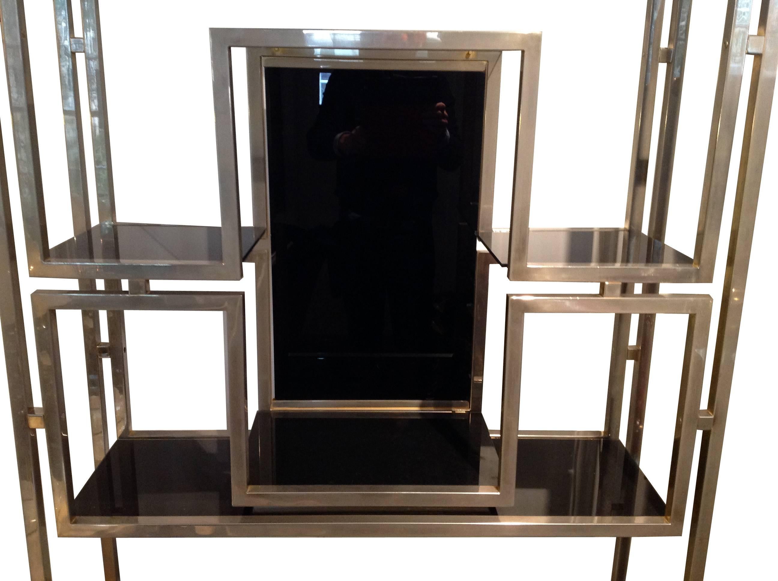 A Kim Moltzer chrome etagere, with central black glass panel and black glass shelving, illuminated with central chrome downlighter. Re wired and PAT tested for UK fittings.