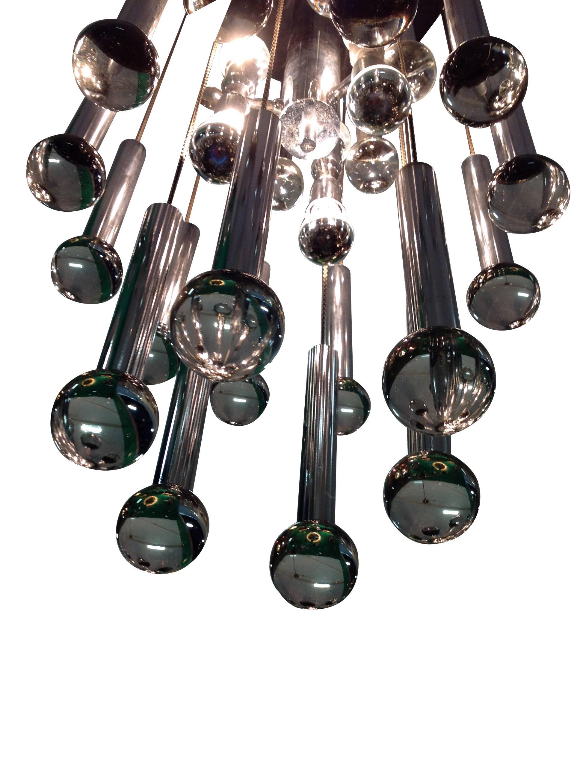 Un lustre Sciolari chromé avec 20 gouttes de verre et de chrome, entourant un luminaire chromé à quatre lumières au centre. Suspendu par des chaînes à une plaque de plafond chromée. Recâblage pour les installations du Royaume-Uni et test PAT. Il