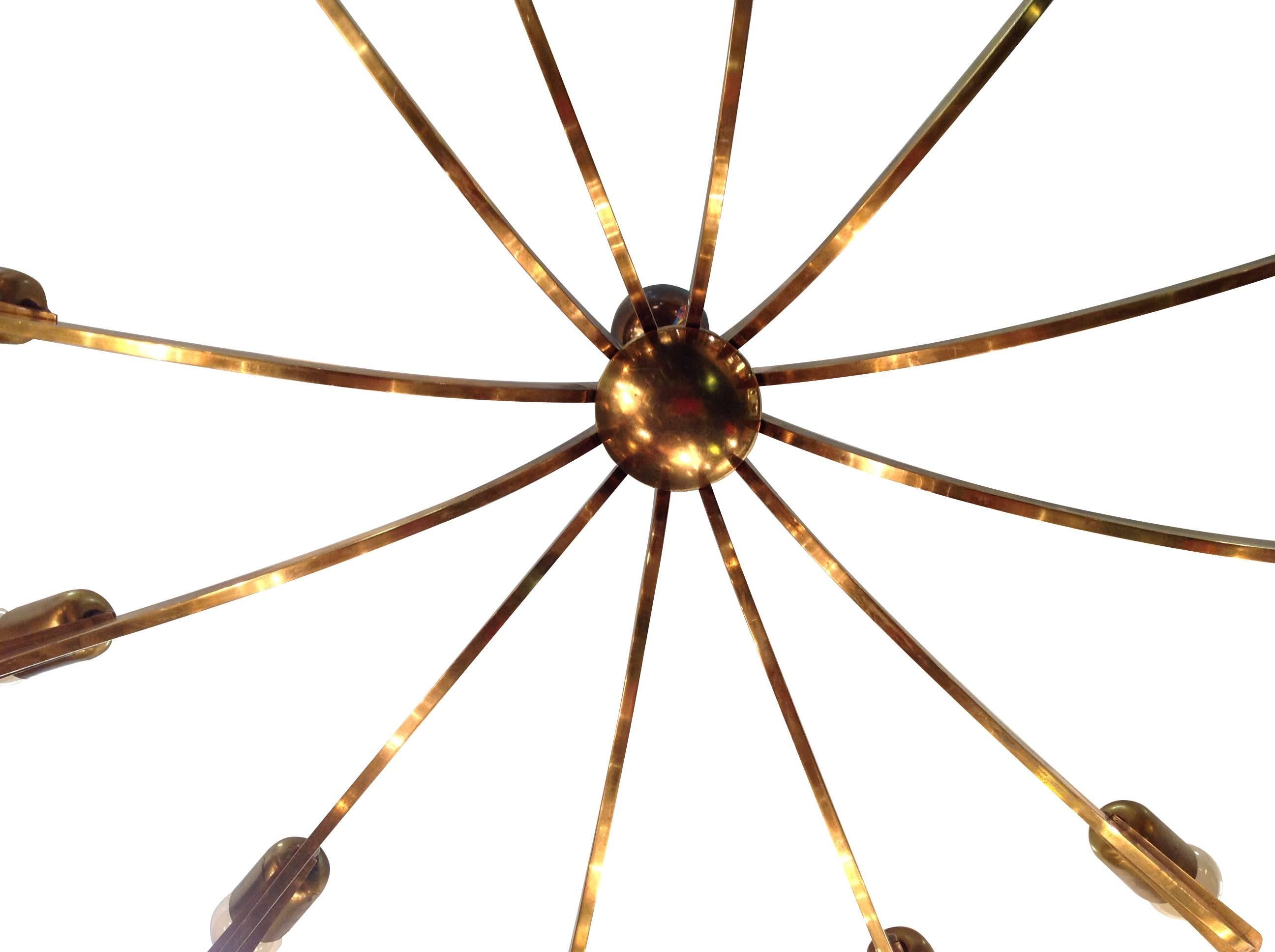 A Stilnovo brass chandelier with 12 arms each with a brass fitting on the end, suspended from a brass domed centre, chain and ceiling fitting. Re-wired and PAT tested with new light fittings on each arm.