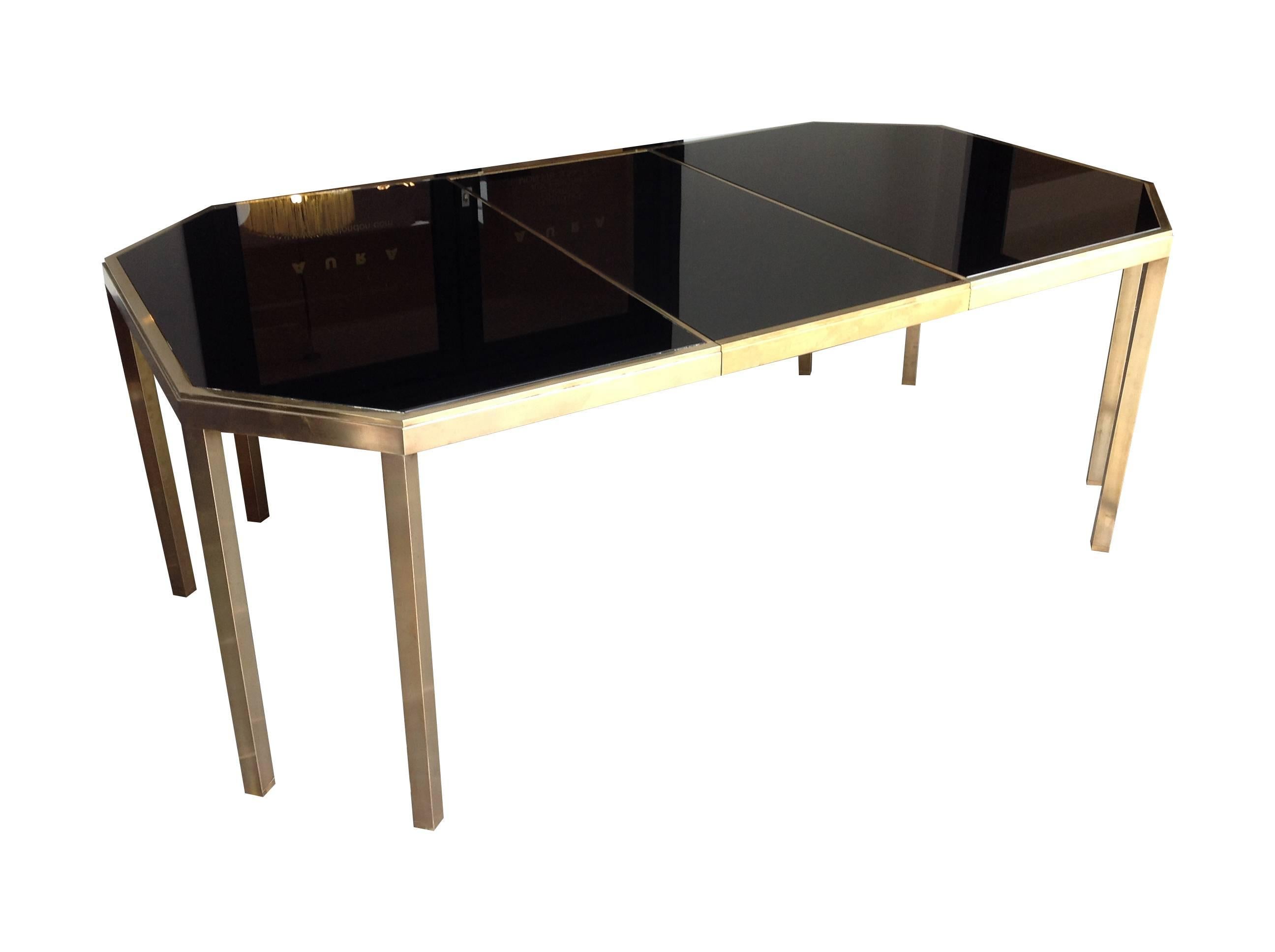 A stunning quality, extendable dining table designed by Guy Lefevre for Maison Jansen, Model name "Alexandra" in solid brass, with black glass top. The table measures 147 cm x 109cm and there are two leaves each with similar brass edging