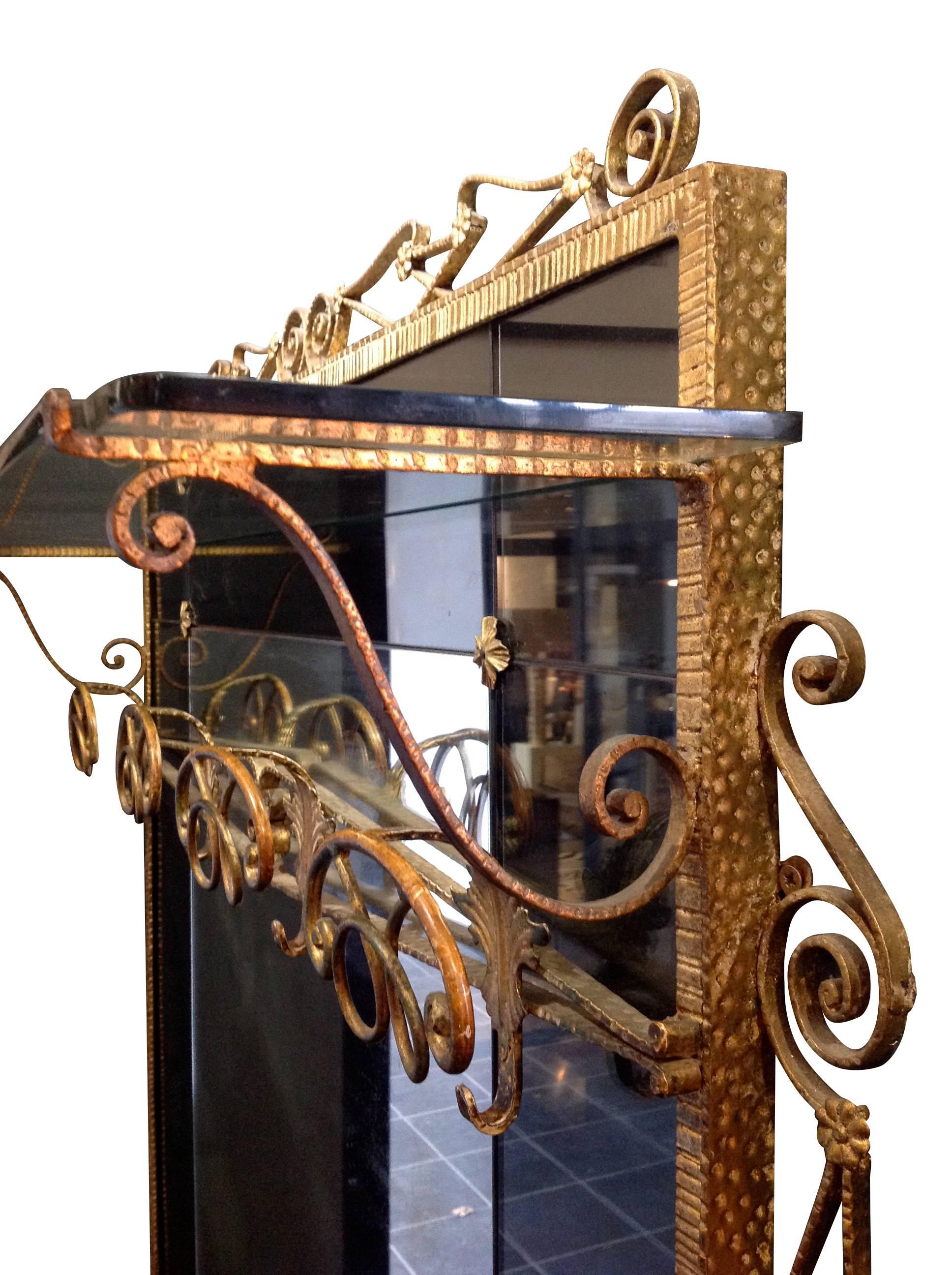 A beautiful Pier Luigi Colli hallway mirror and coat stand with clear central mirror plate surrounded by smoke green mirror surround with wrought iron flower details and decorative wrtought iron gilt frame. There is a row of four ornate coat and