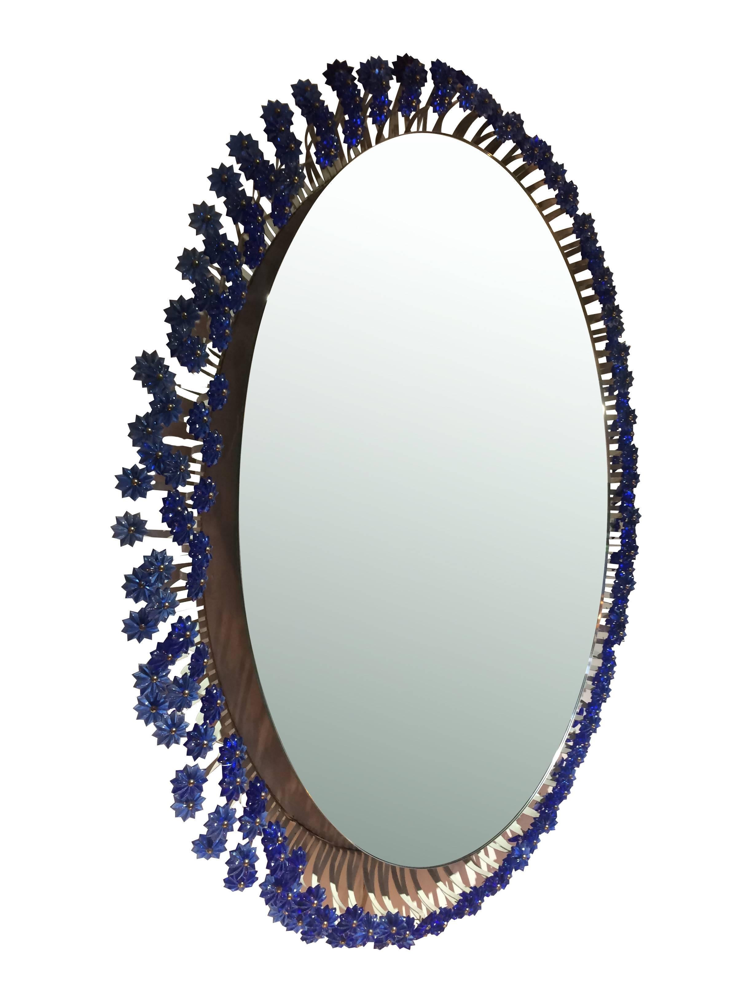 A beautiful Emil Stejnar back lit mirror for Rupert Nikoll, Austria, 1960s. The mirrors has a rare blue Murano glass flower surround, each flower mounted on white enamel metal stems, with brass centre pin. Behind the mirror are six lights and has