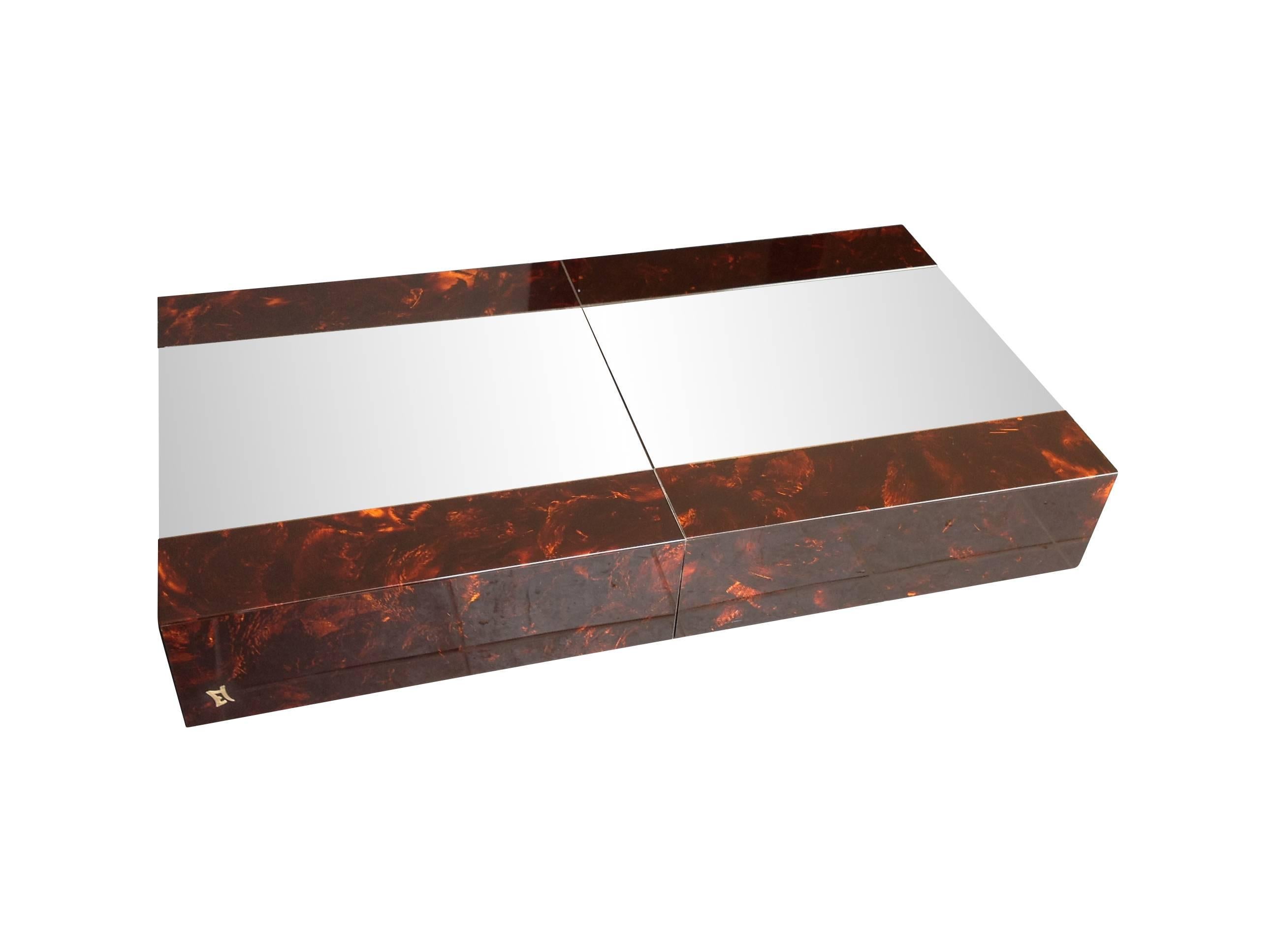 An Eric Maville and Jean Claude Mahey sliding coffee table with mirrored top and clad in faux tortoise shell acrylic. The top slides open to reveal a mirrored and chrome hidden bar with 2 levels for bottles and glasses. Signed with brass 