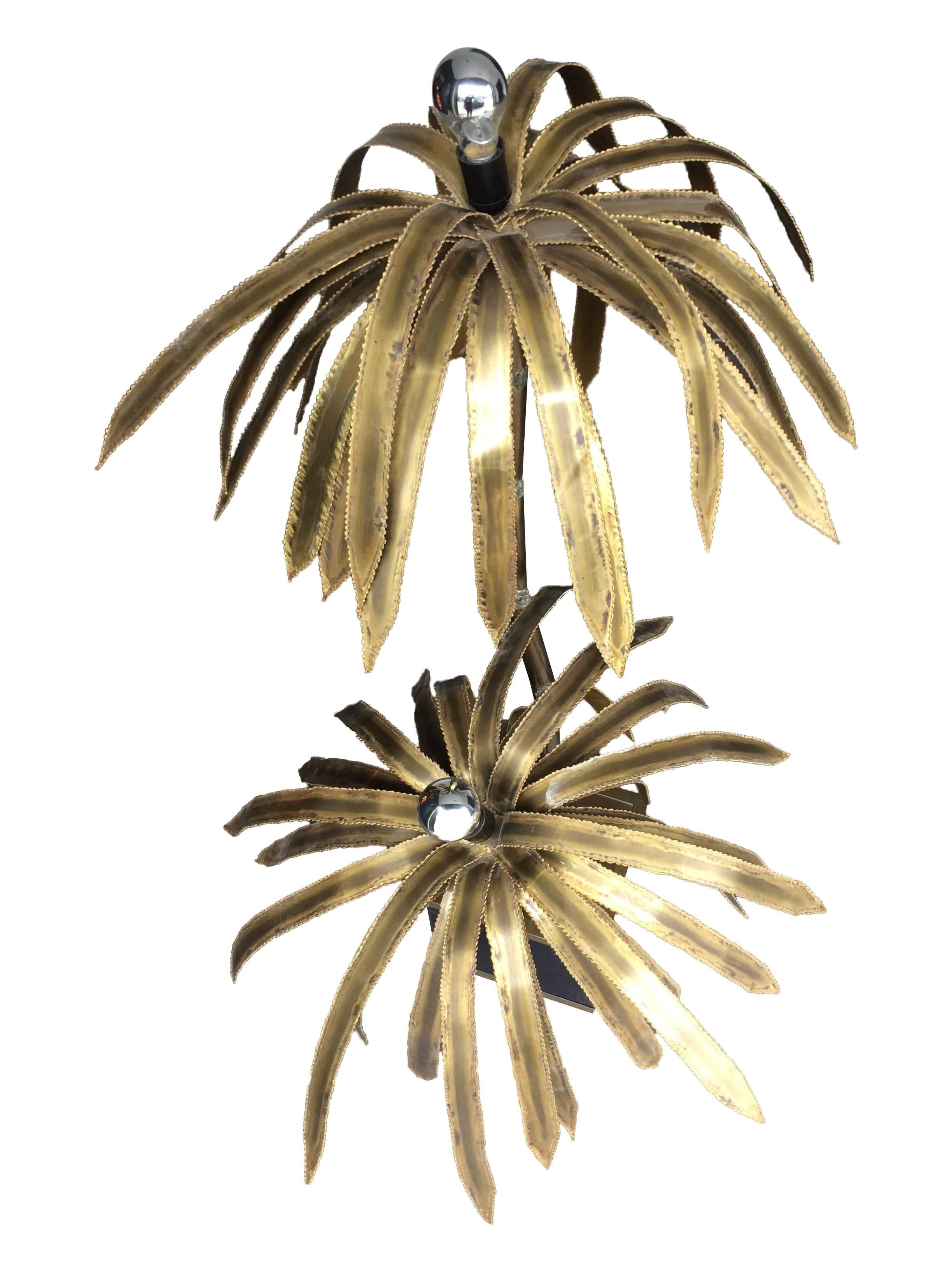 A Maison Jansen double palm tree floor lamp with two palm trees each with torch cut brass fronds, with a central bulb in each, coming off a faux bamboo metal trunk and mounted on a brass and black felt covered base. 
Re wired with black cord flex