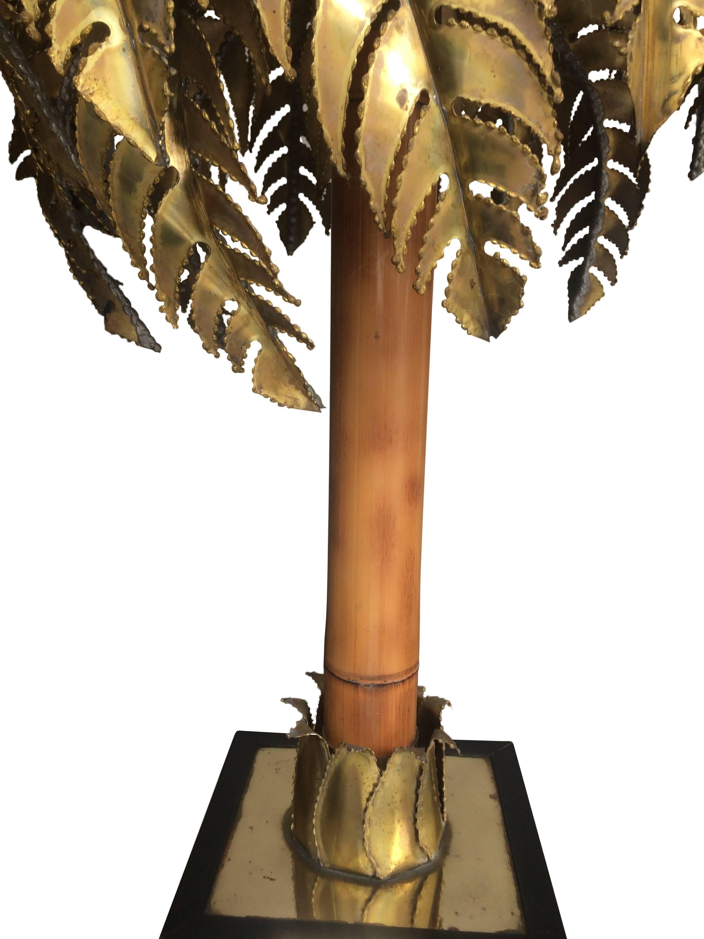 A Maison Jansen palm tree table lamp with rare real bamboo trunk, brass torch cut leaves in a black gloss laminated and brass base. Rewired with new fittings and antique gold cord flex and pat tested.