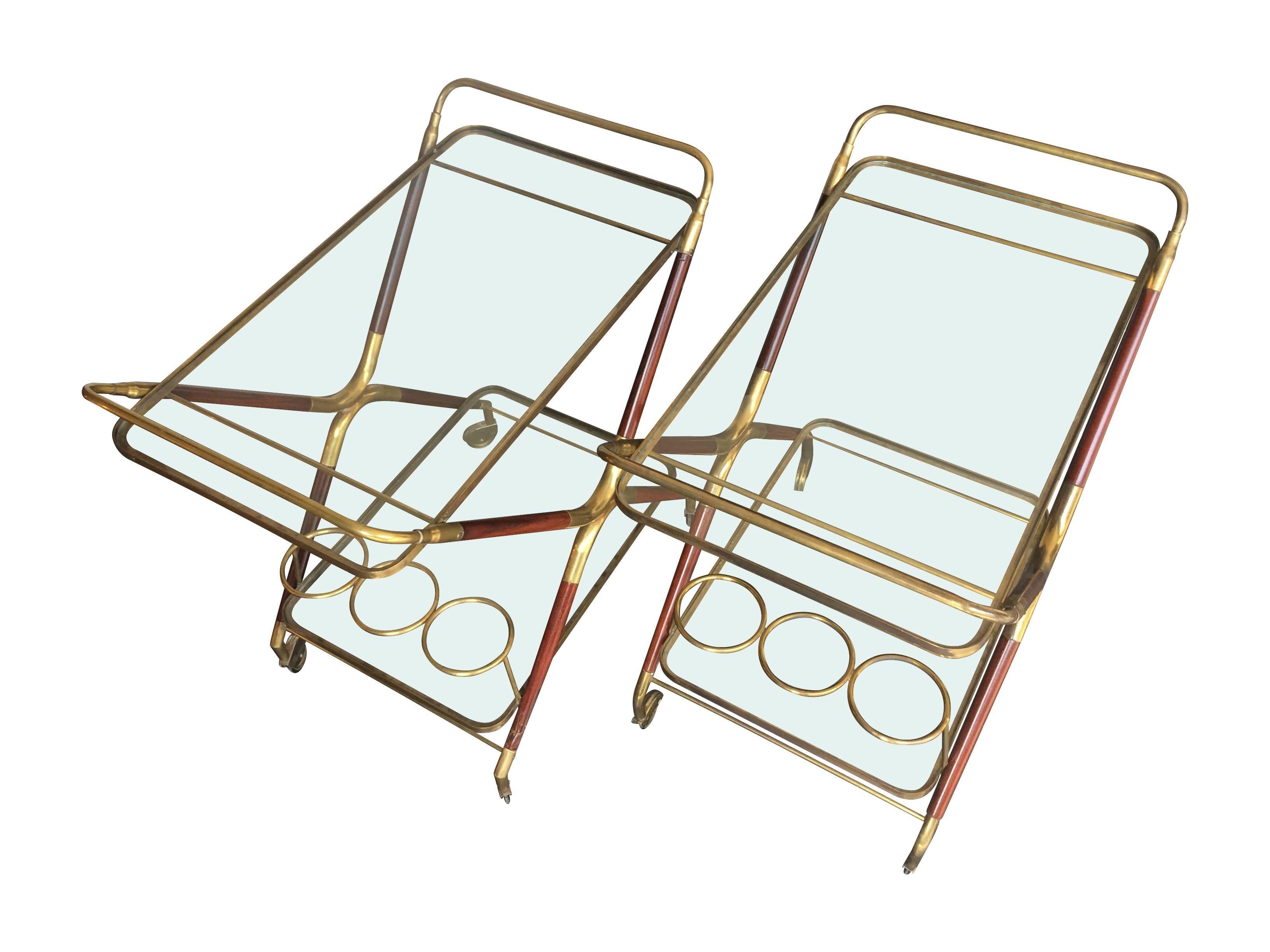 A Cesare Lacca Italian bar cart, with brass and varnished rosewood frames with two glass shelves, the lower of which has three brass bottle holders, with original castors.